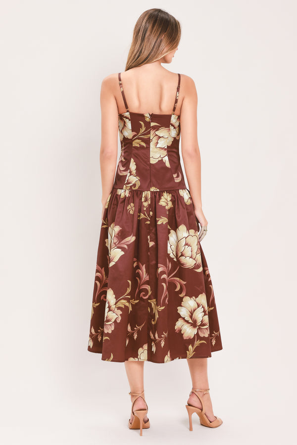 A woman modeling a sleeveless midi dress with a burgundy base and a large beige floral print | Flying Tomato