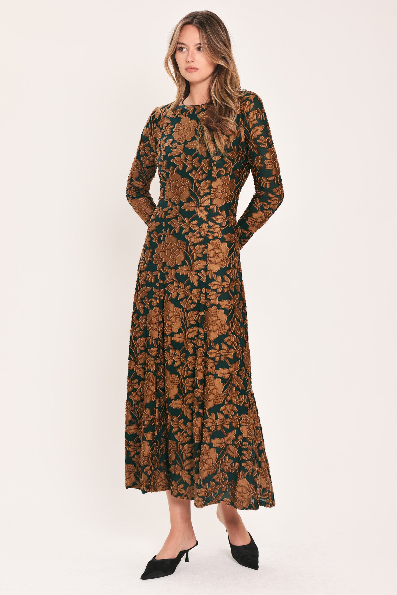 A woman modeling a long-sleeve midi dress with a brown and dark green floral pattern | FLying Tomato