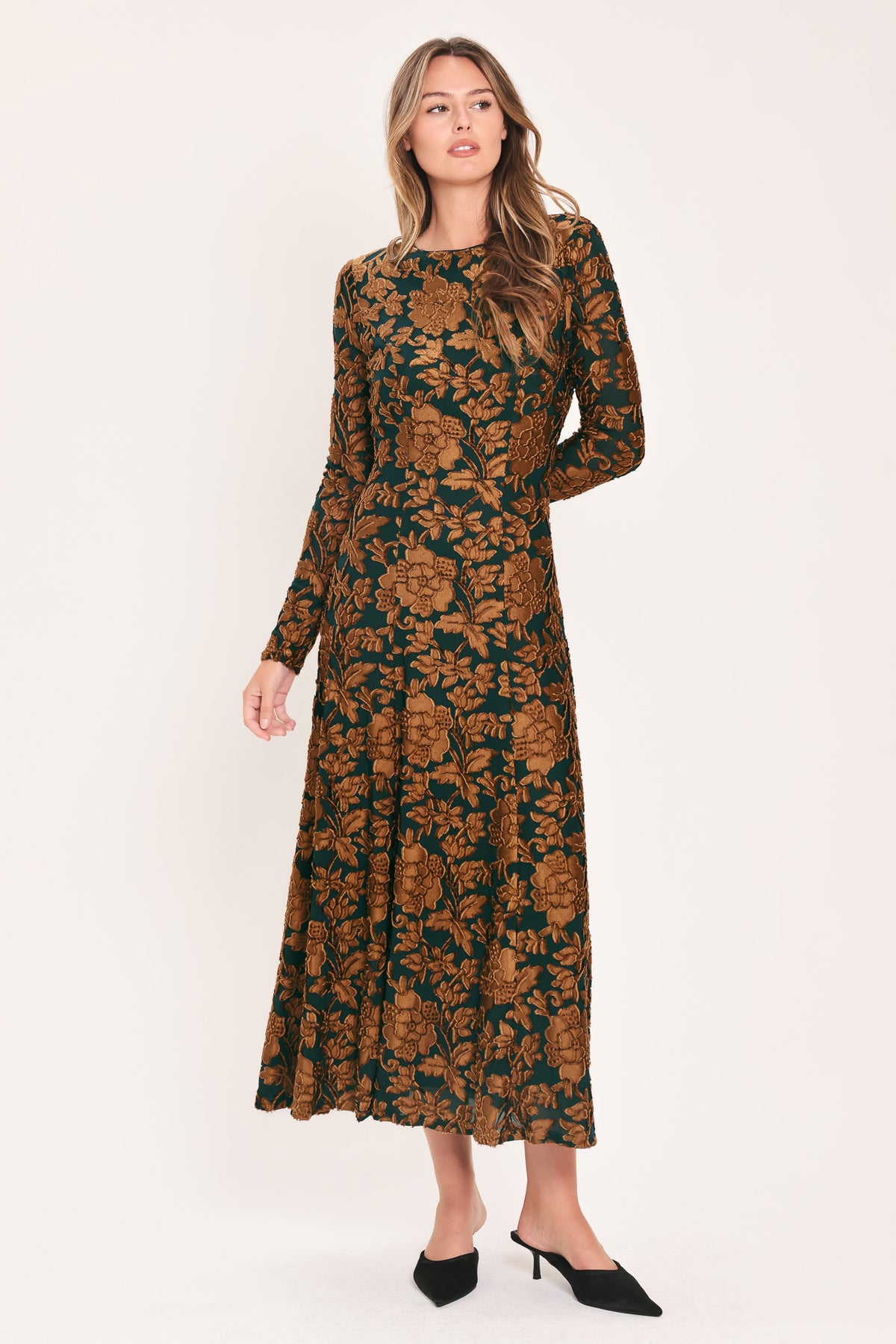 A woman modeling a long-sleeve midi dress with a brown and dark green floral pattern | FLying Tomato