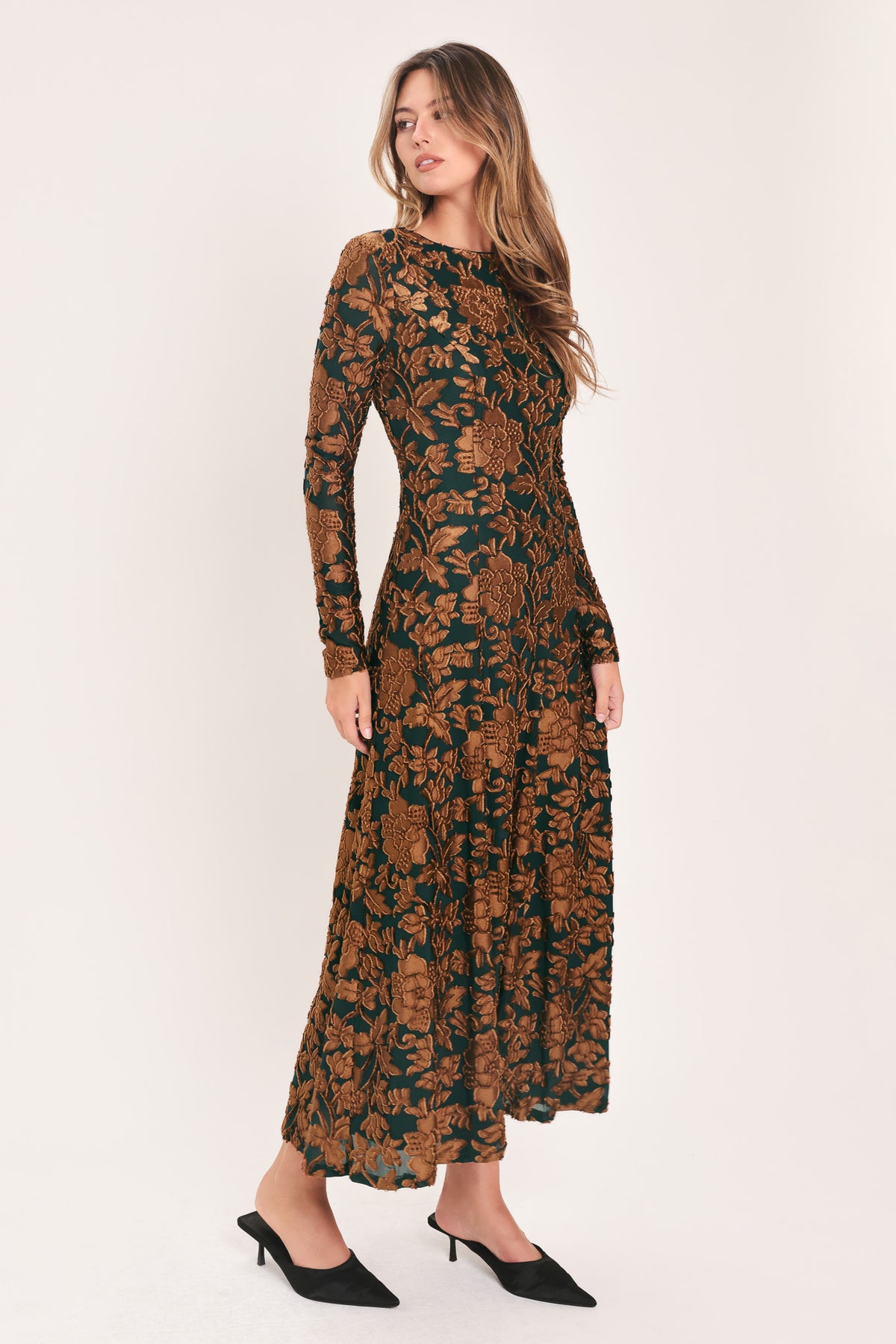 A woman modeling a long-sleeve midi dress with a brown and dark green floral pattern | FLying Tomato