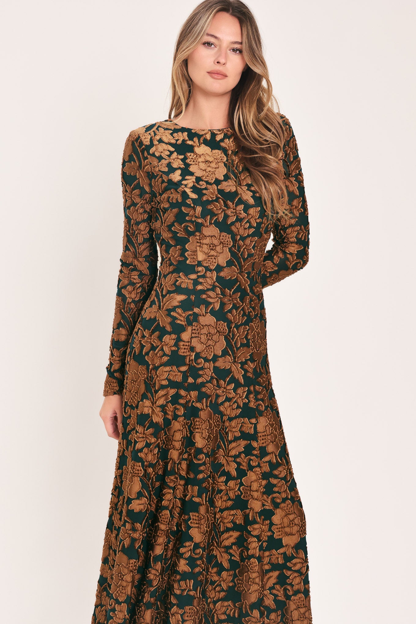 A woman modeling a long-sleeve midi dress with a brown and dark green floral pattern | FLying Tomato