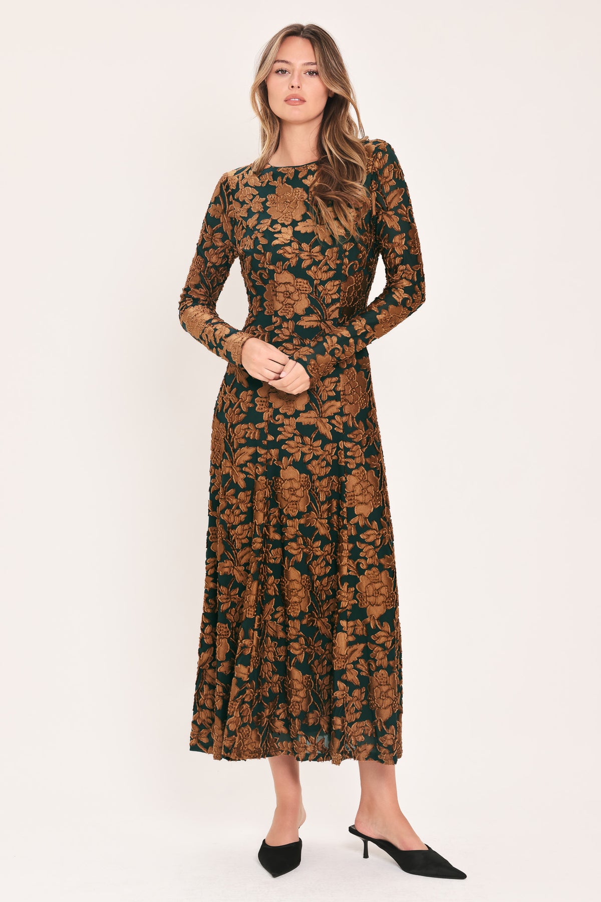 A woman modeling a long-sleeve midi dress with a brown and dark green floral pattern | FLying Tomato