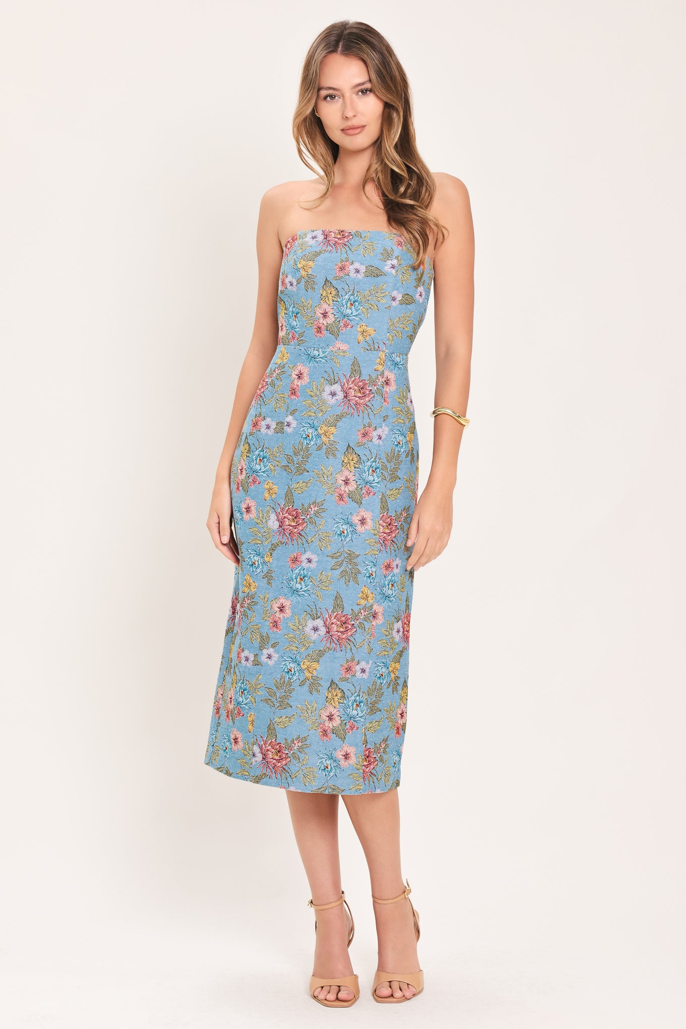 A woman models a strapless midi dress with a light blue base and a colorful floral pattern | Flying Tomato