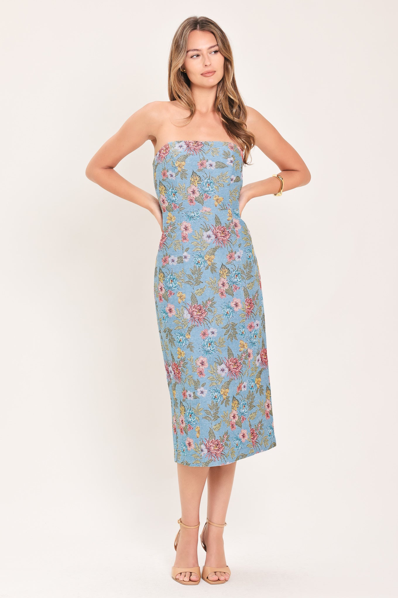 A woman models a strapless midi dress with a light blue base and a colorful floral pattern | Flying Tomato