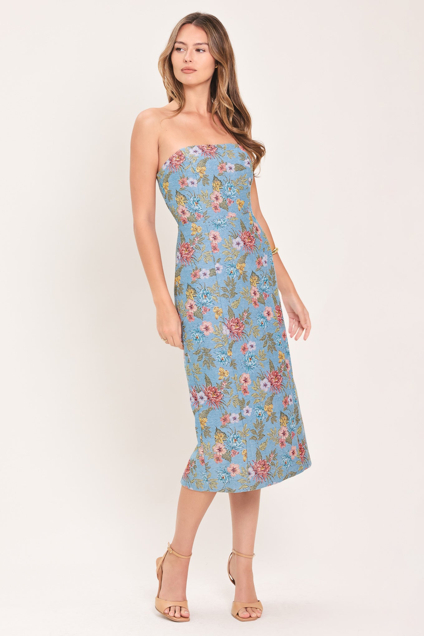 A woman models a strapless midi dress with a light blue base and a colorful floral pattern | Flying Tomato