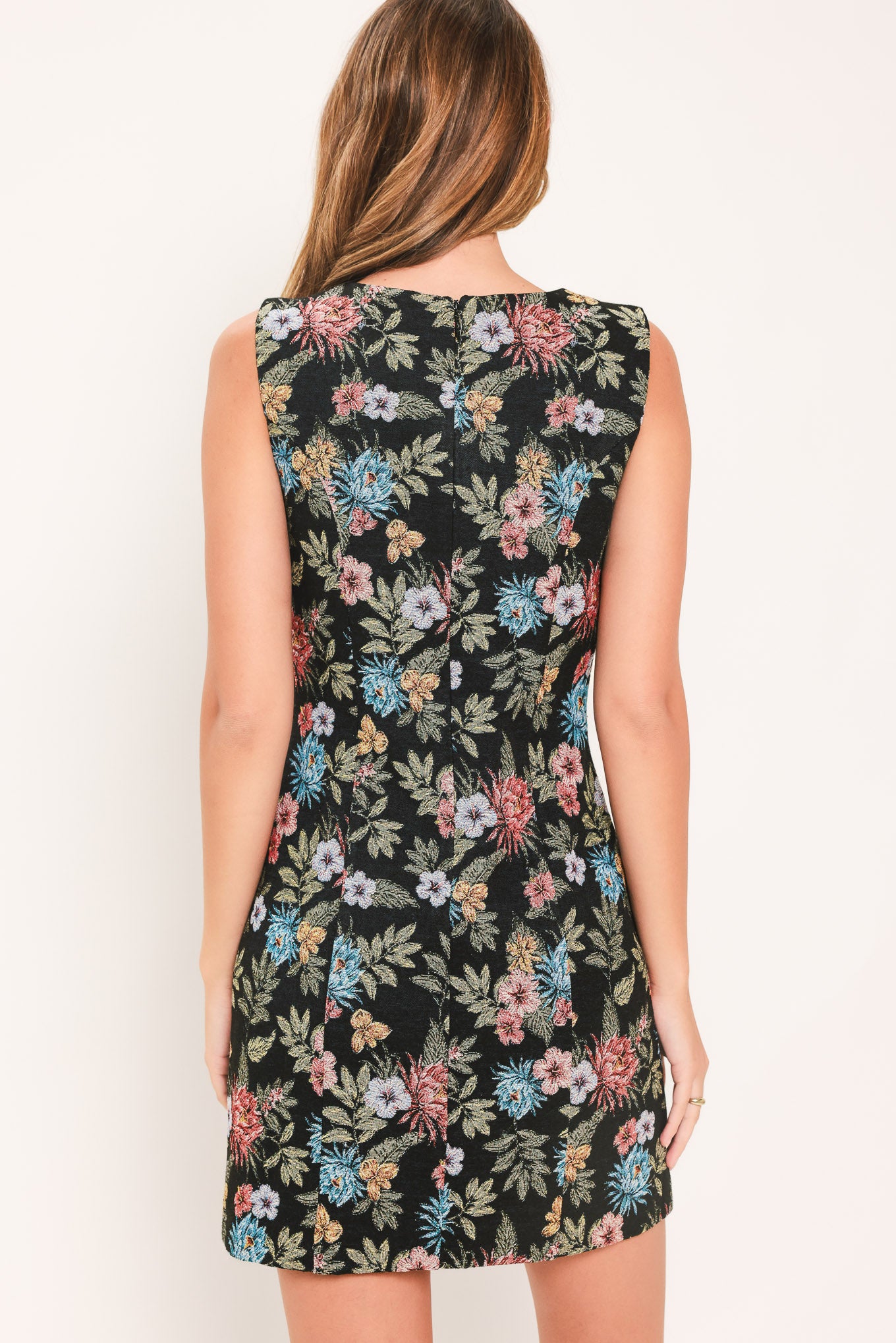 A woman modeling a sleeveless black mini dress with a colorful floral print | Flying Tomato