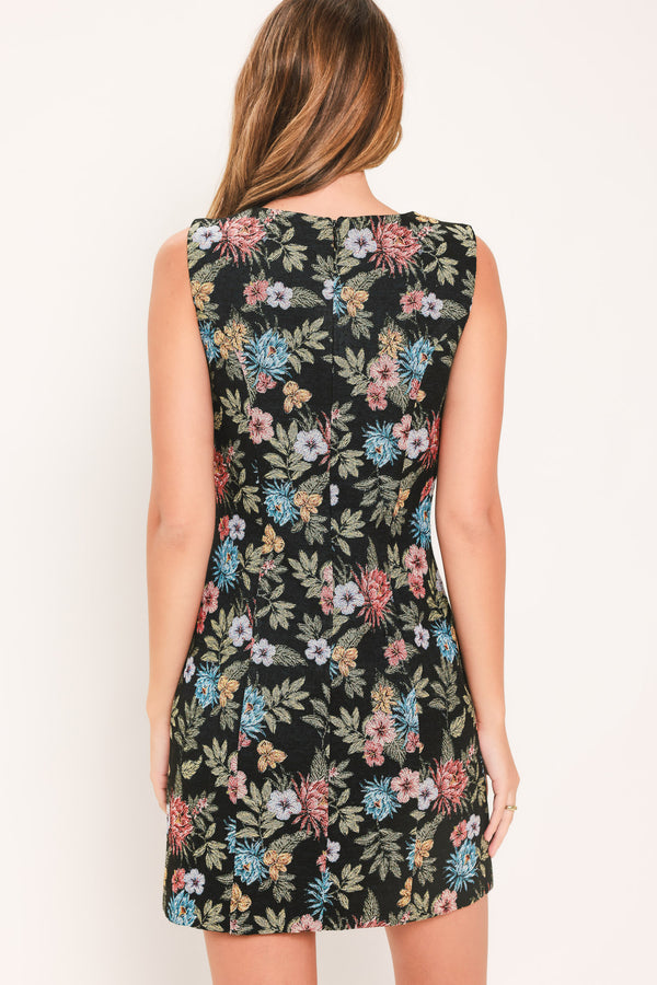 A woman modeling a sleeveless black mini dress with a colorful floral print | Flying Tomato