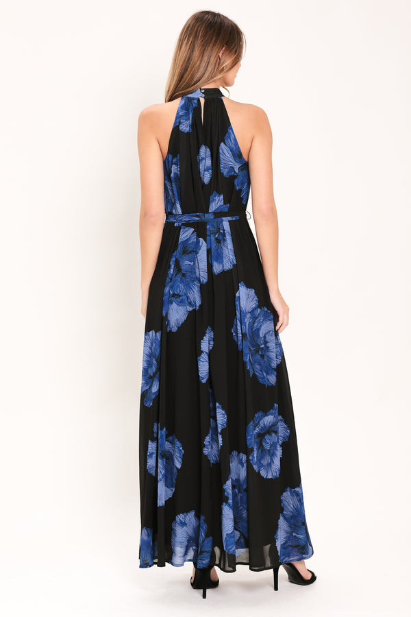 Woman wearing a black maxi dress with blue floral pattern, back neck button closure, and self sash tie | Flying Tomato
