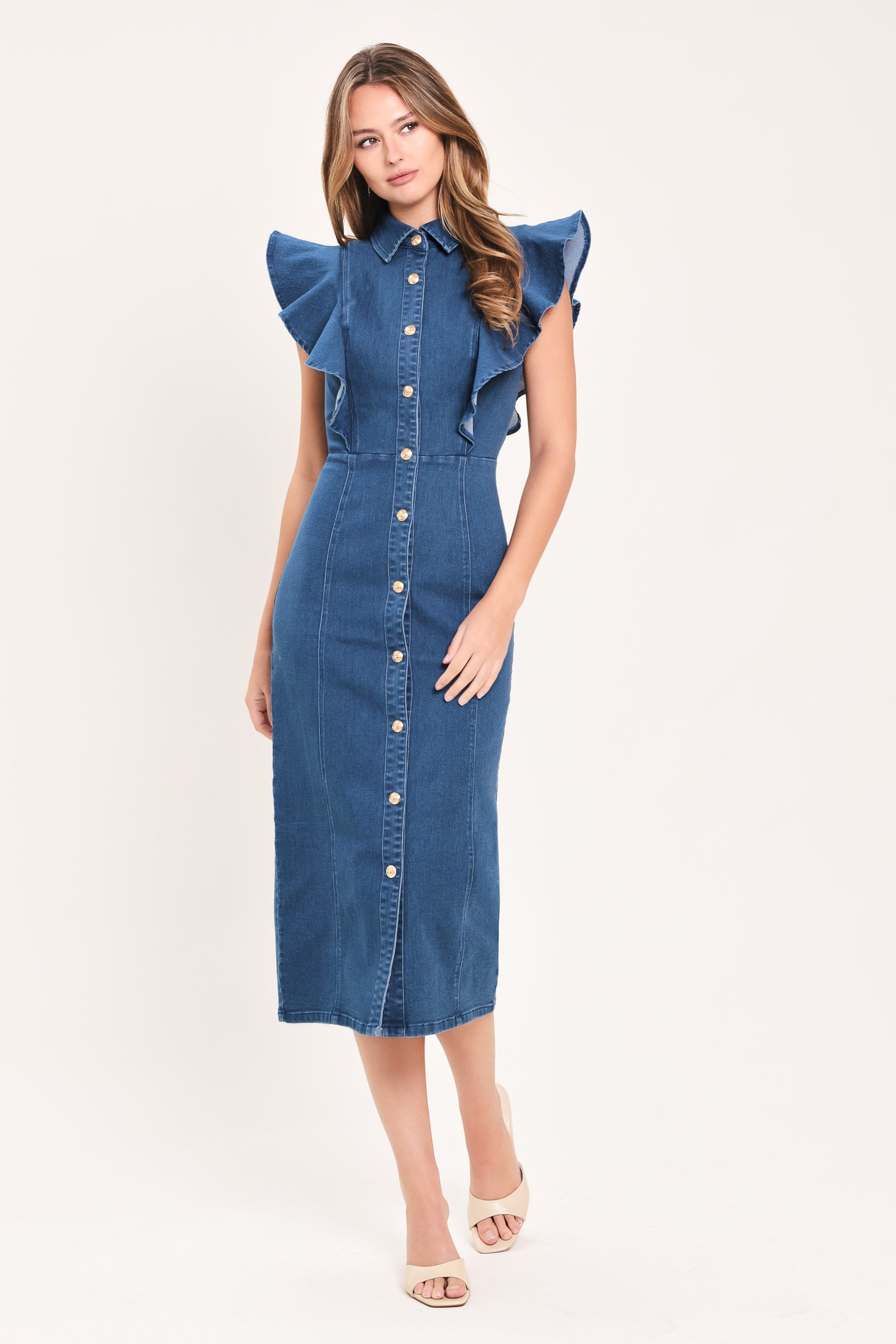A woman wearing a blue denim midi dress with ruffled cap sleeves, a button-down front, and a pointed collar | Flying Tomato