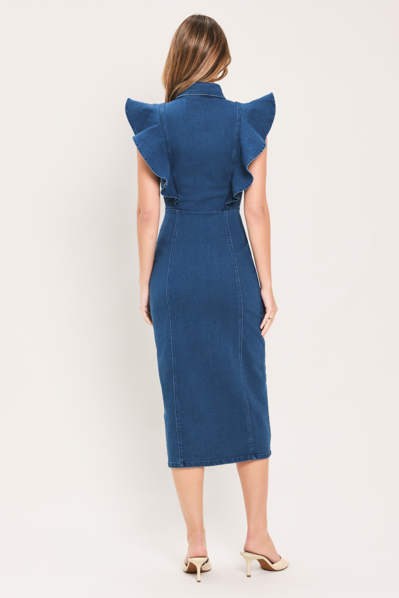 A woman wearing a blue denim midi dress with ruffled cap sleeves, a button-down front, and a pointed collar | Flying Tomato
