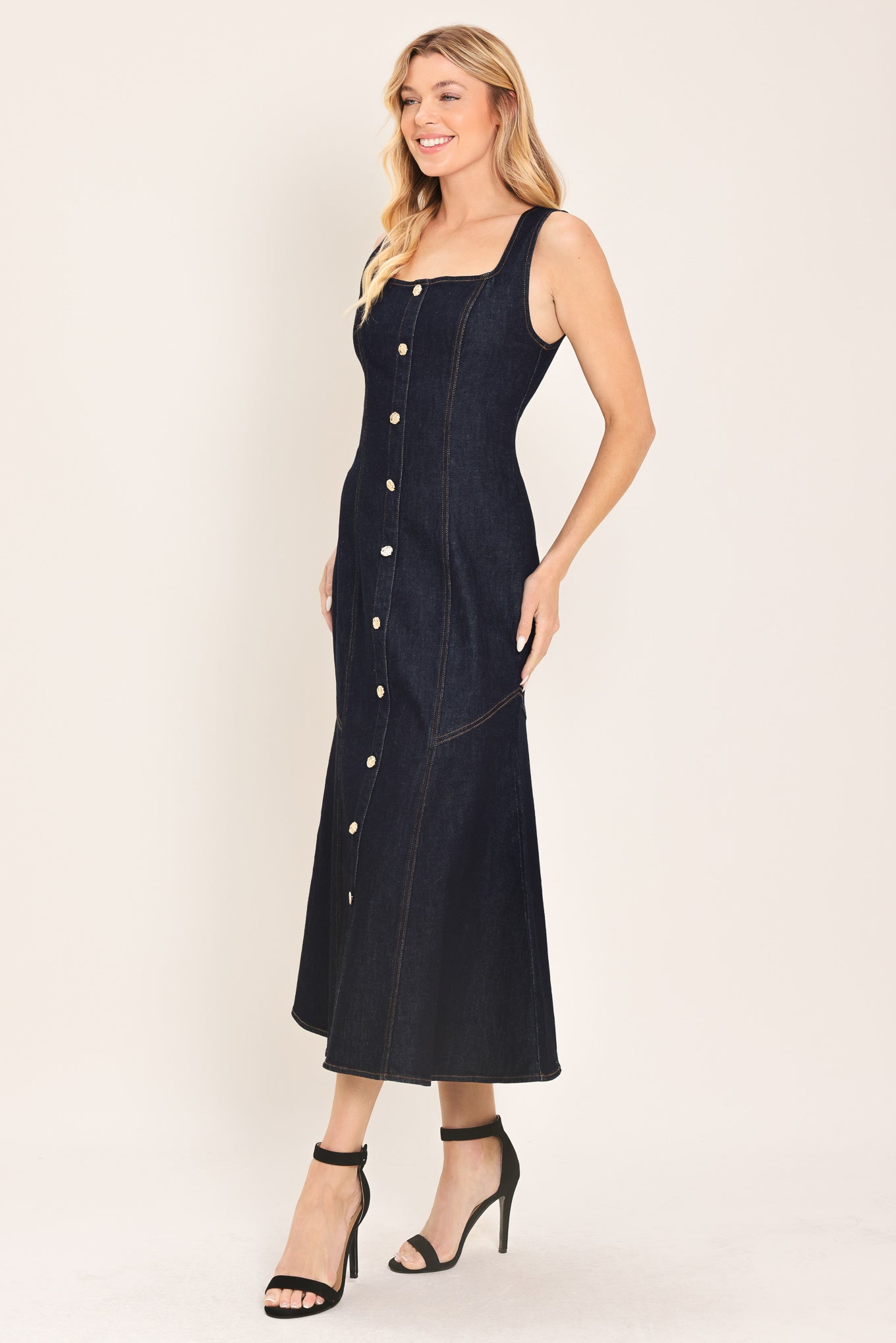 Woman wearing a dark indigo denim sleeveless midi dress with buttons | Flying Tomato