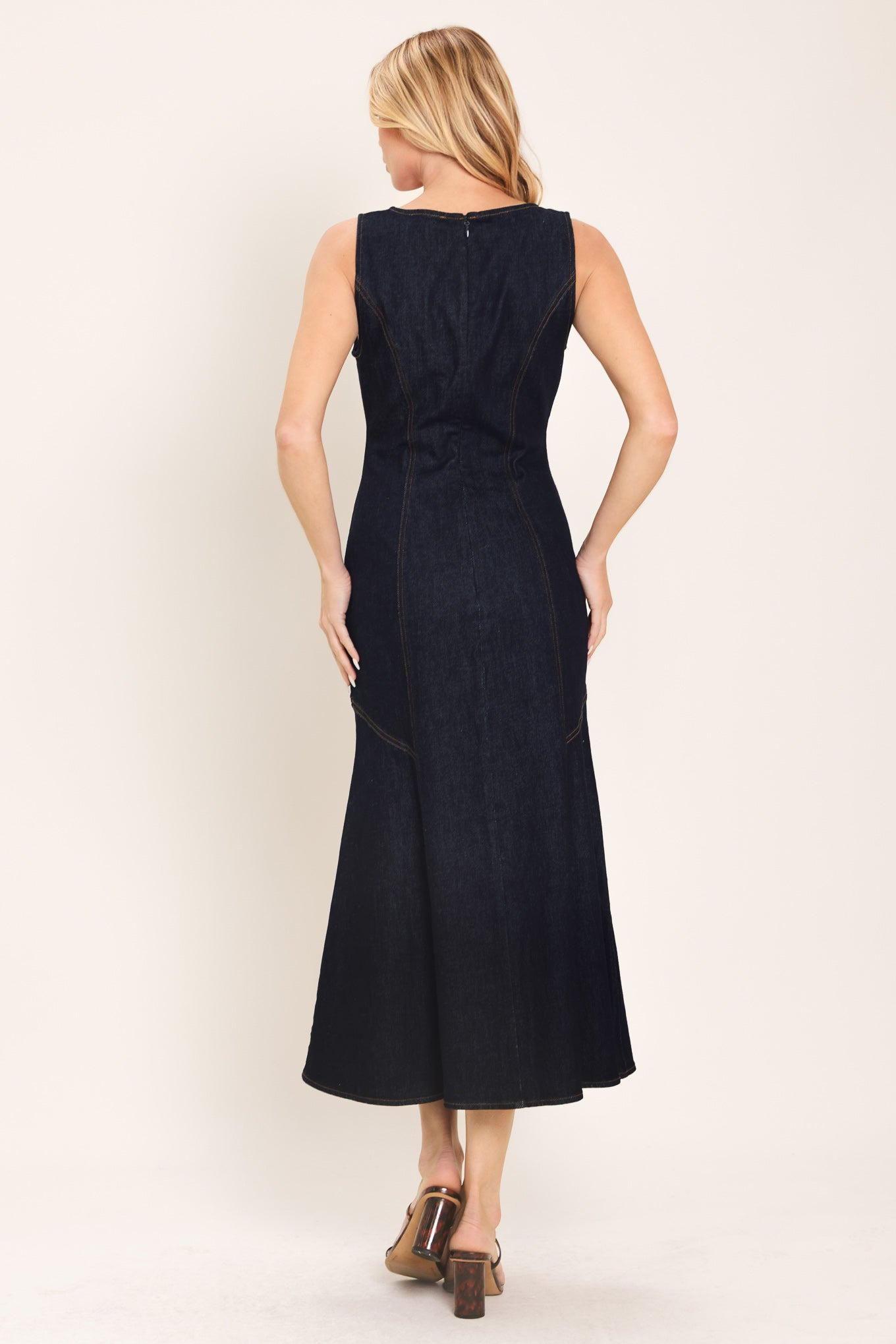 Woman wearing a dark indigo denim sleeveless midi dress with buttons | Flying Tomato