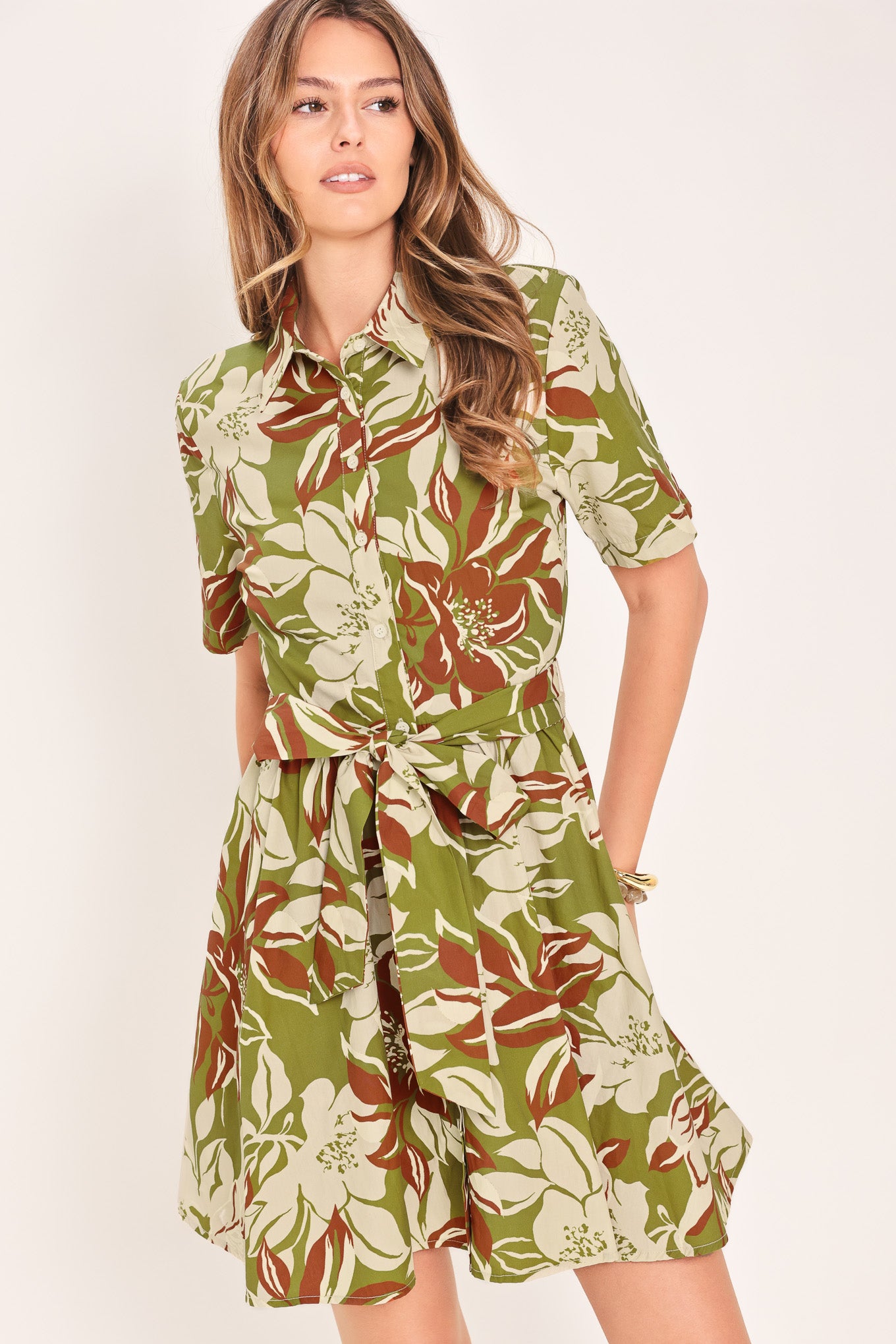 Woman wearing an olive green floral mini shirt dress with front button closure, short sleeve, self sash and full skirt | Flying Tomato