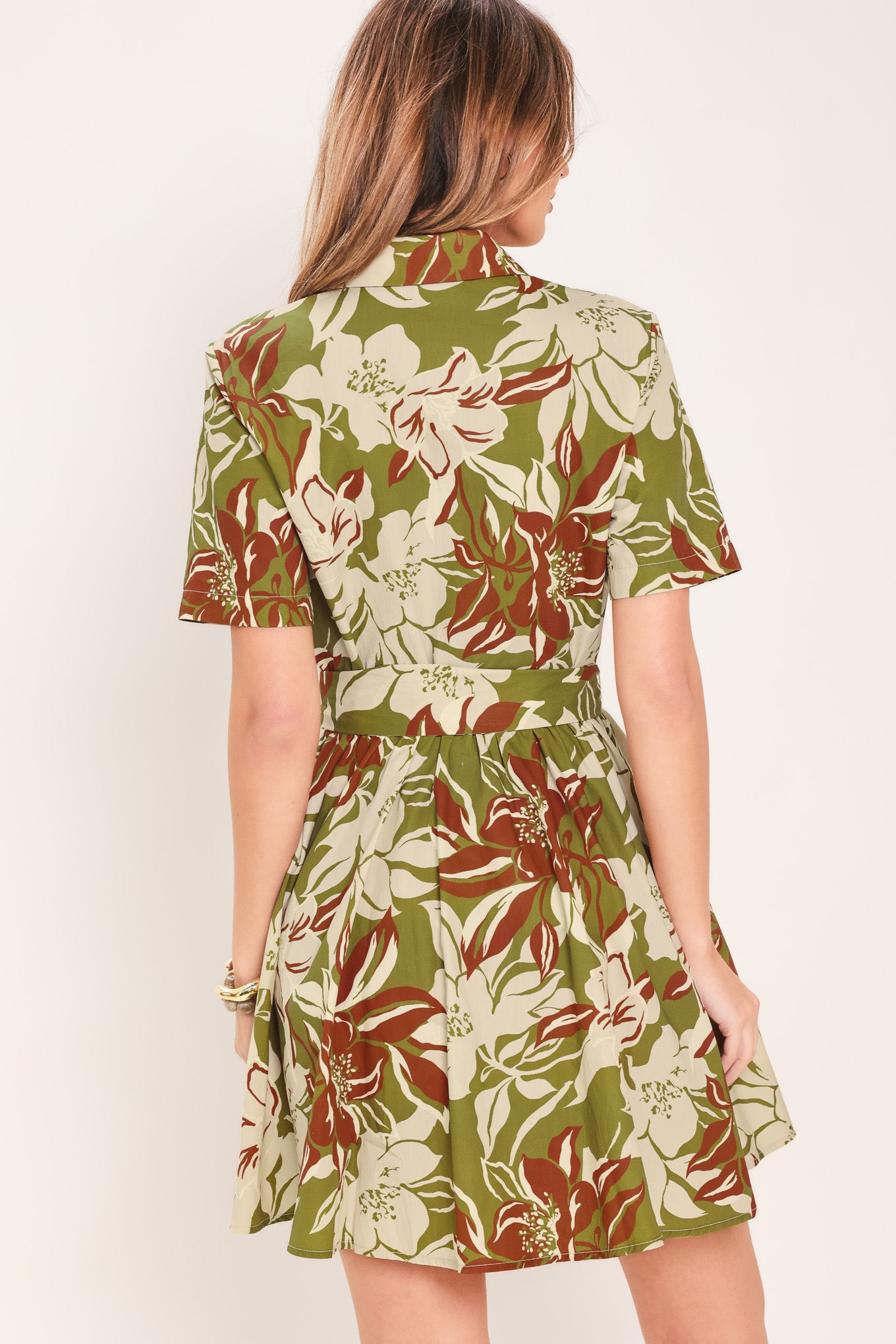 Woman wearing an olive green floral mini shirt dress with front button closure, short sleeve, self sash and full skirt | Flying Tomato