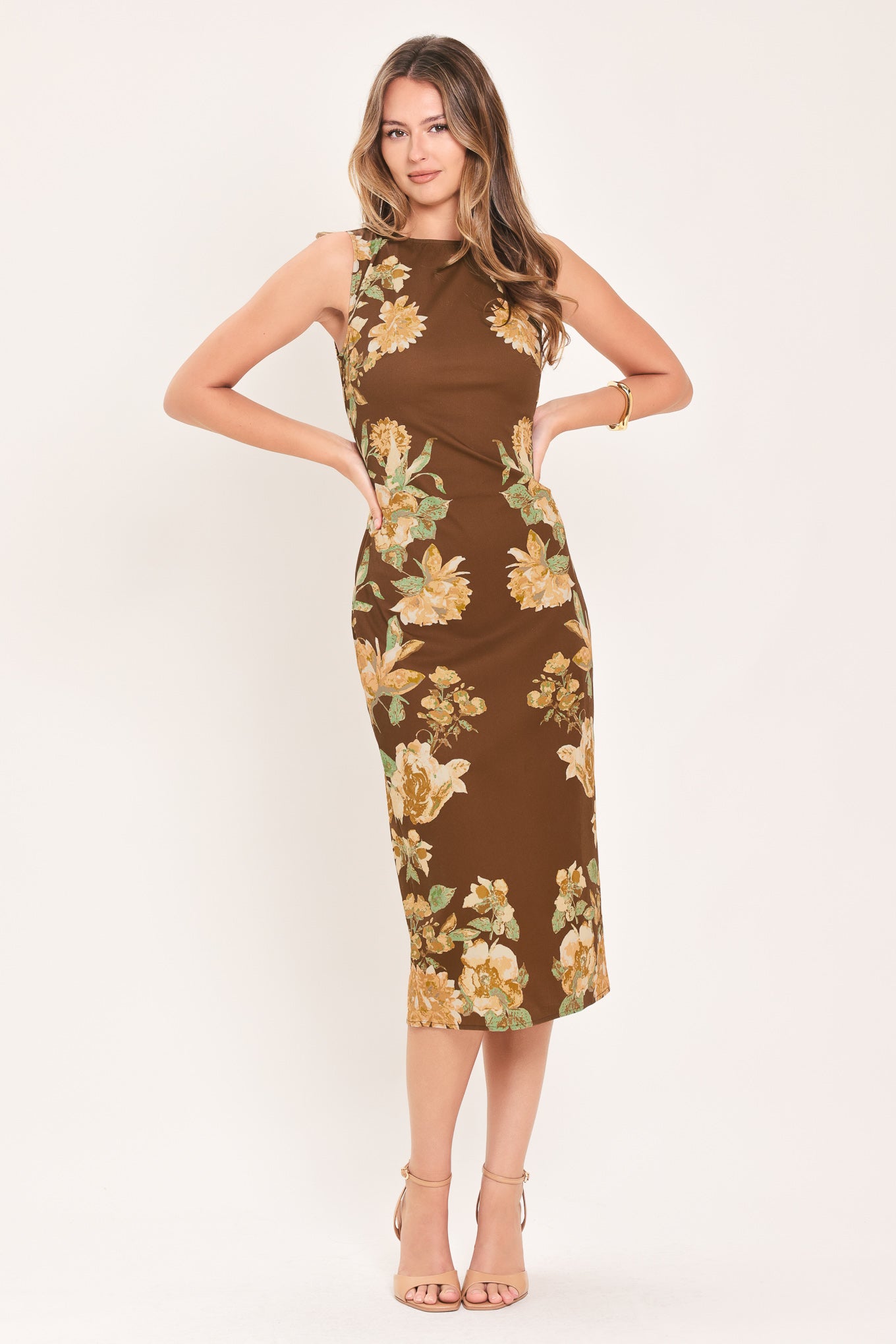 A woman modeling a sleeveless brown midi dress with a large yellow and green floral print | Flying Tomato