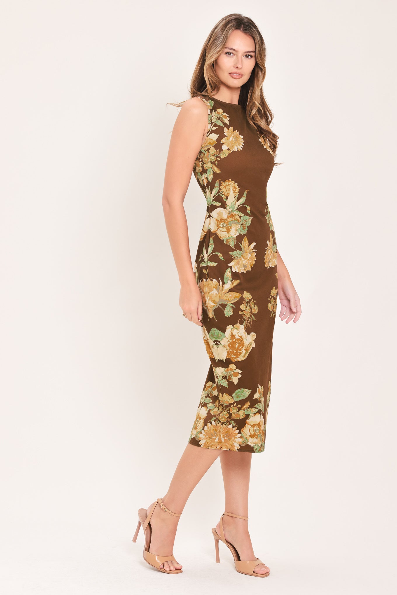 A woman modeling a sleeveless brown midi dress with a large yellow and green floral print | Flying Tomato