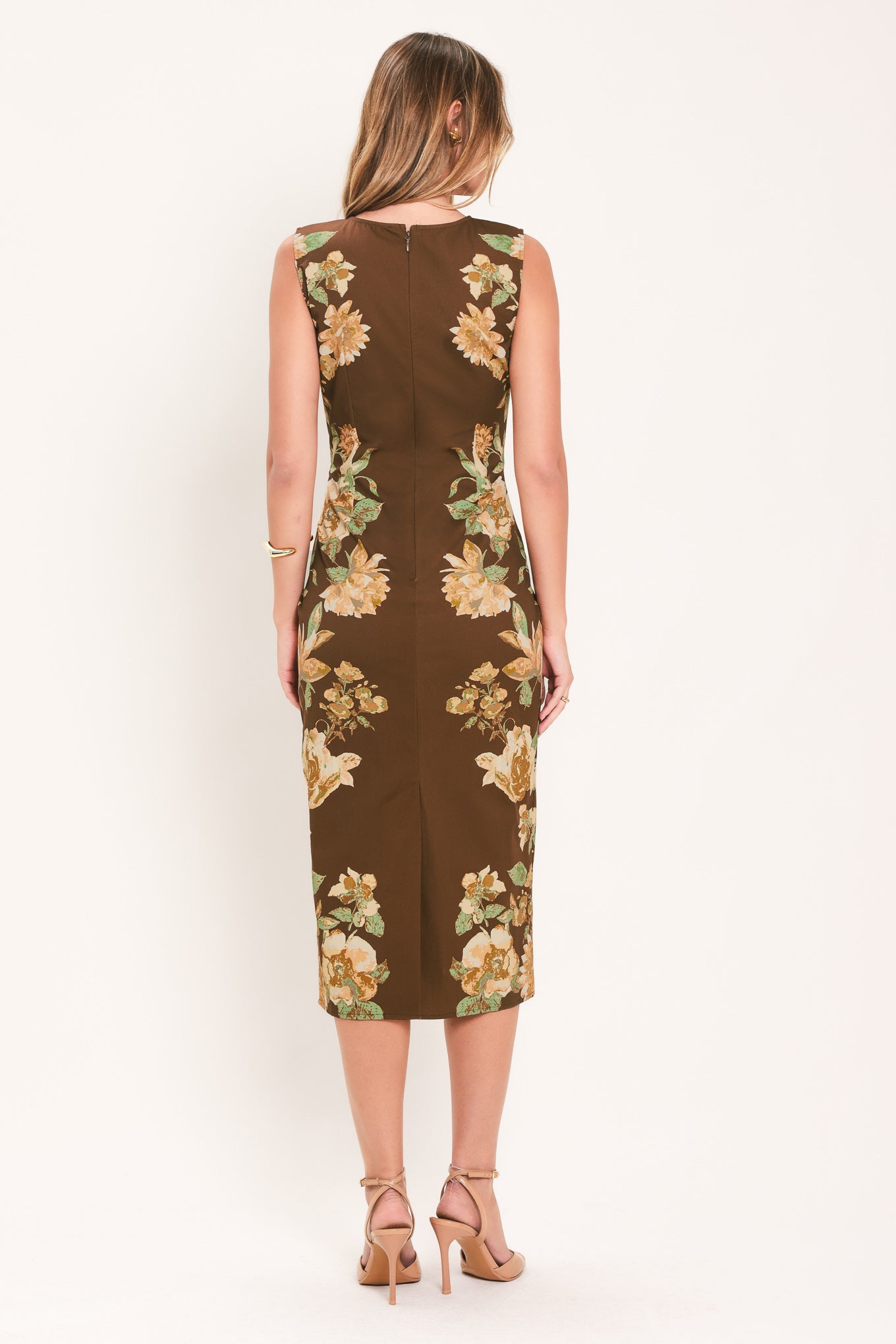A woman modeling a sleeveless brown midi dress with a large yellow and green floral print | Flying Tomato