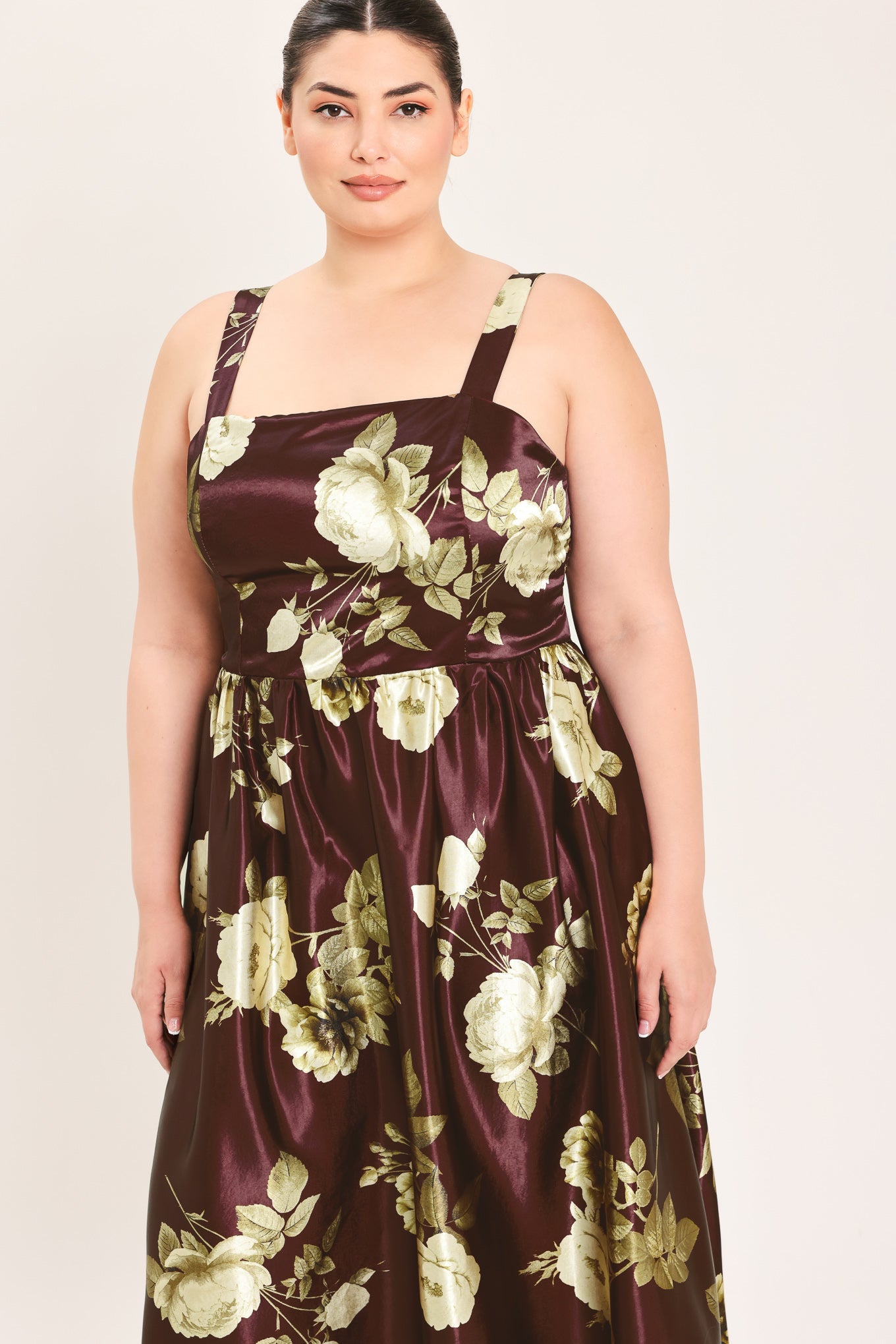 A woman modeling a sleeveless midi dress with a brown satin-like base and a large cream and olive floral print | Flying Tomato Curve