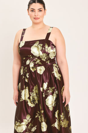 A woman modeling a sleeveless midi dress with a brown satin-like base and a large cream and olive floral print | Flying Tomato Curve