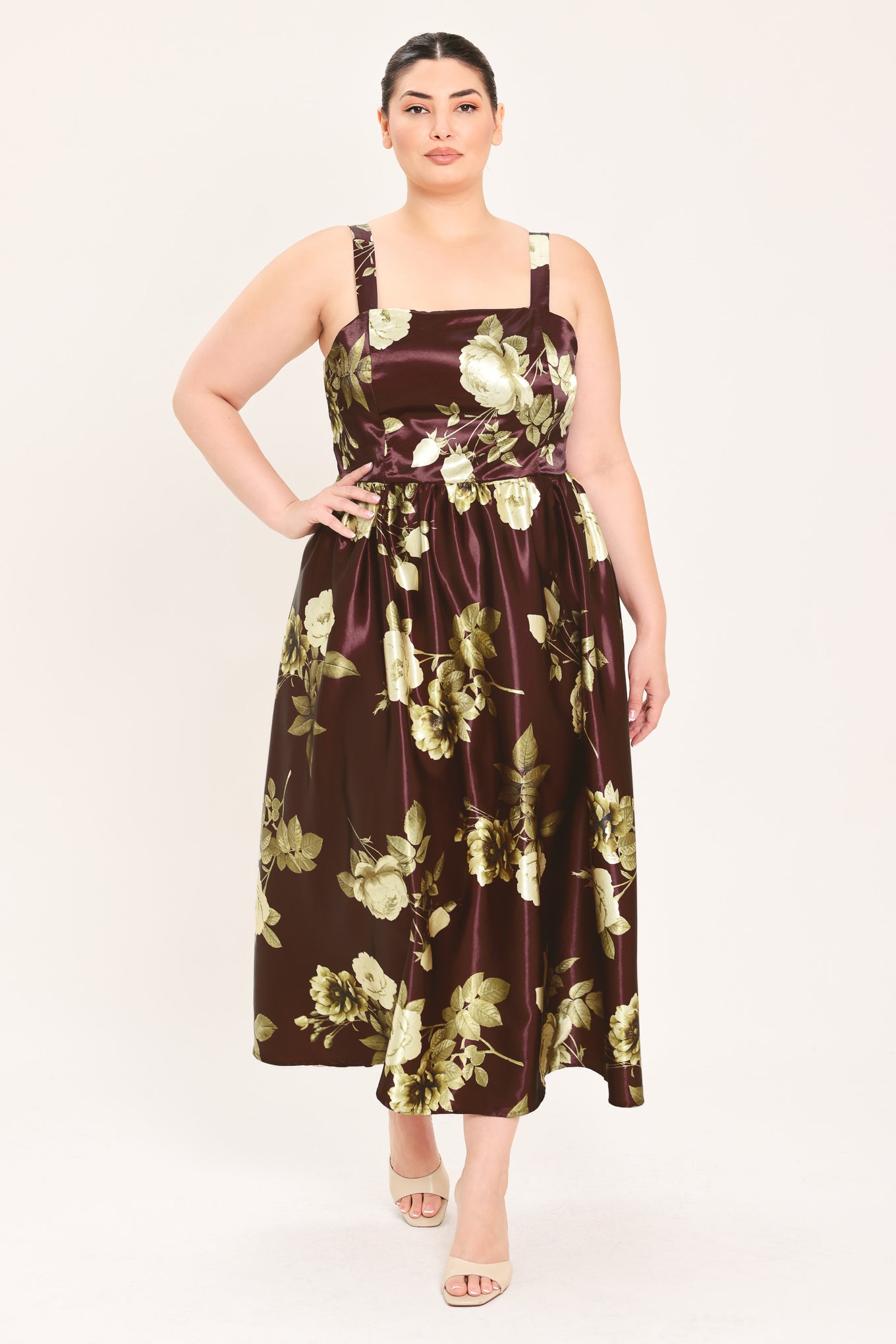 A woman modeling a sleeveless midi dress with a brown satin-like base and a large cream and olive floral print | Flying Tomato Curve