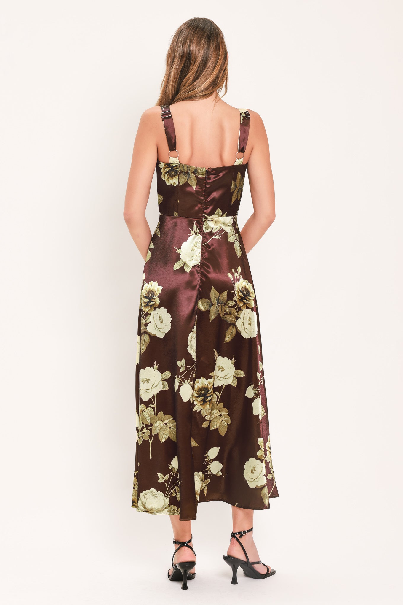 A woman modeling a sleeveless midi dress with a brown satin-like base and a large cream and olive floral print | Flying Tomato