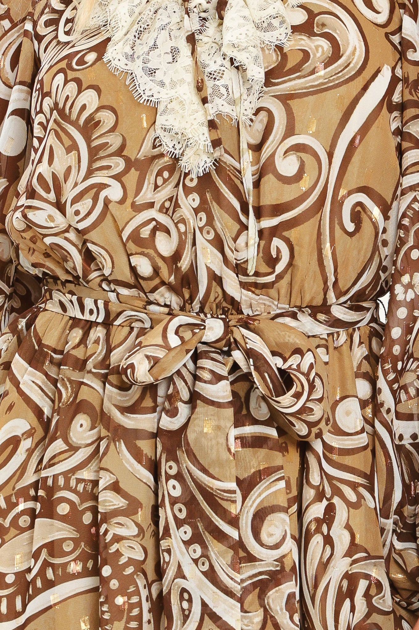 A woman wearing a long-sleeve camel mini dress with a brown and beige paisley pattern, featuring a white lace ruffle collar and a matching fabric tie belt at the waist | Flying Tomato