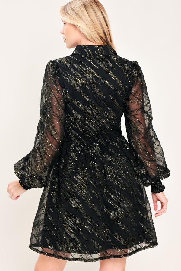 A model wearing a black sheer mini dress with gold glittery diagonal stripes, featuring long balloon sleeves and a flared skirt | Flying Tomato
