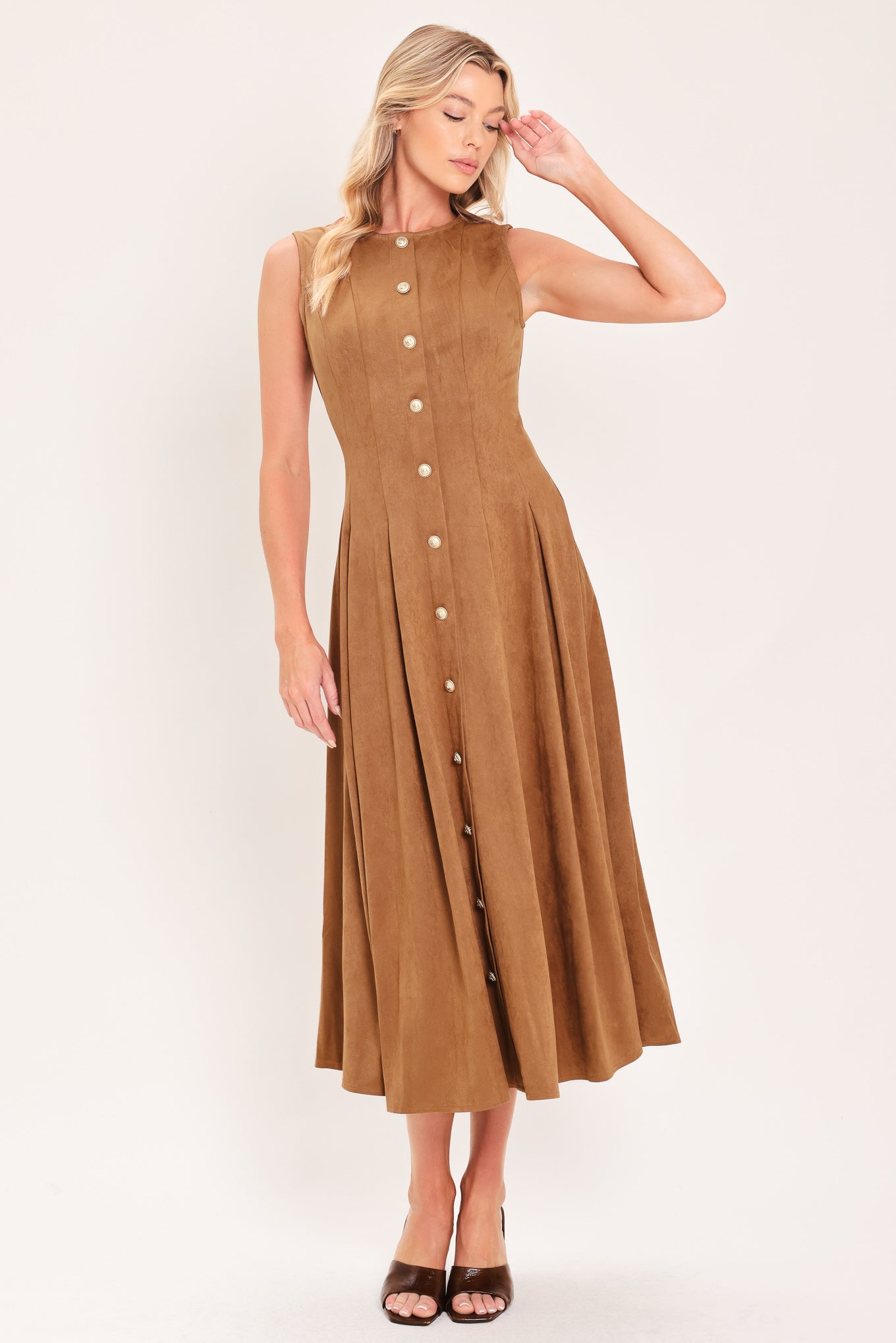 A woman modeling a sleeveless, midi-length camel brown faux suede dress with a button-down front | Flying Tomato