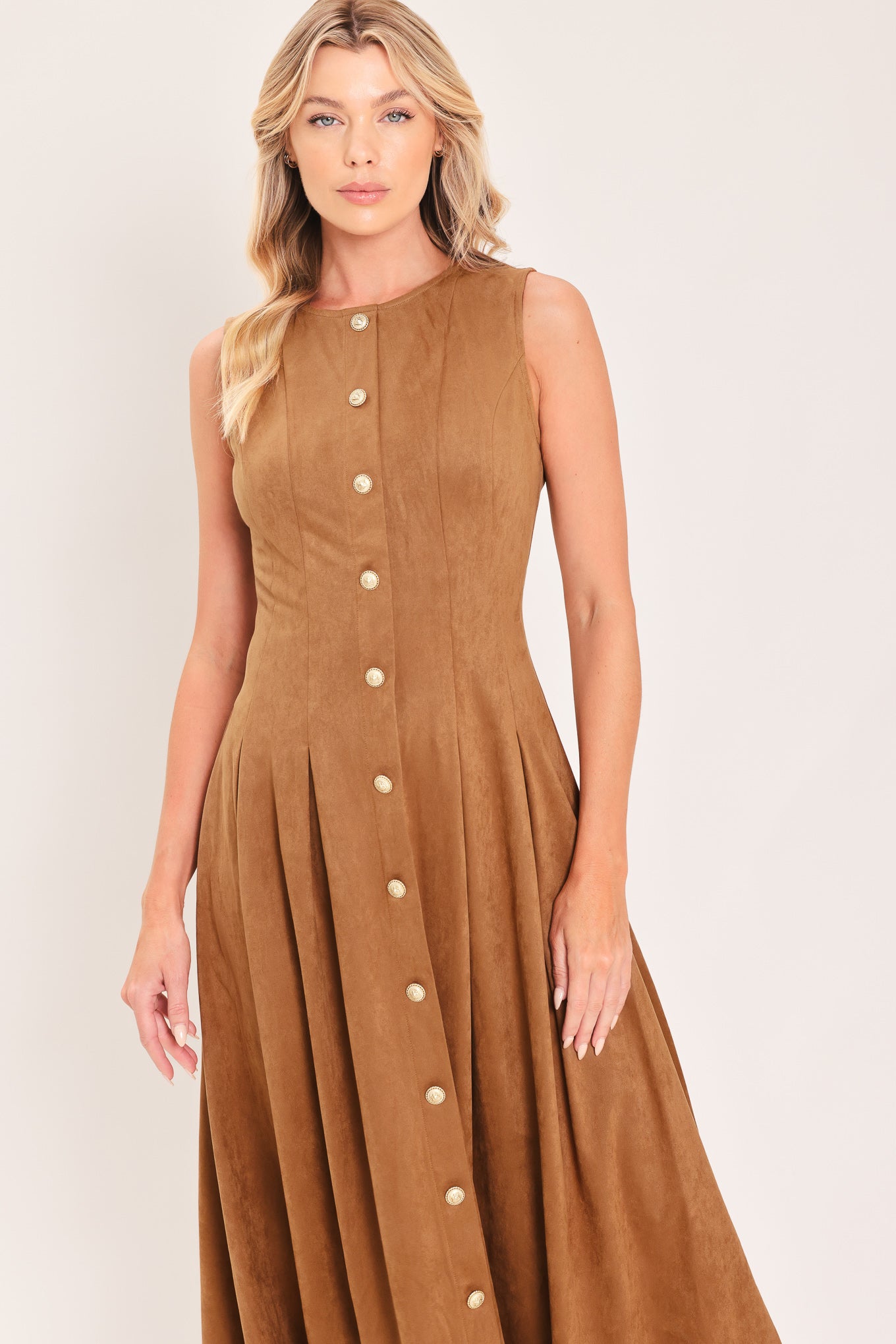 A woman modeling a sleeveless, midi-length camel brown faux suede dress with a button-down front | Flying Tomato