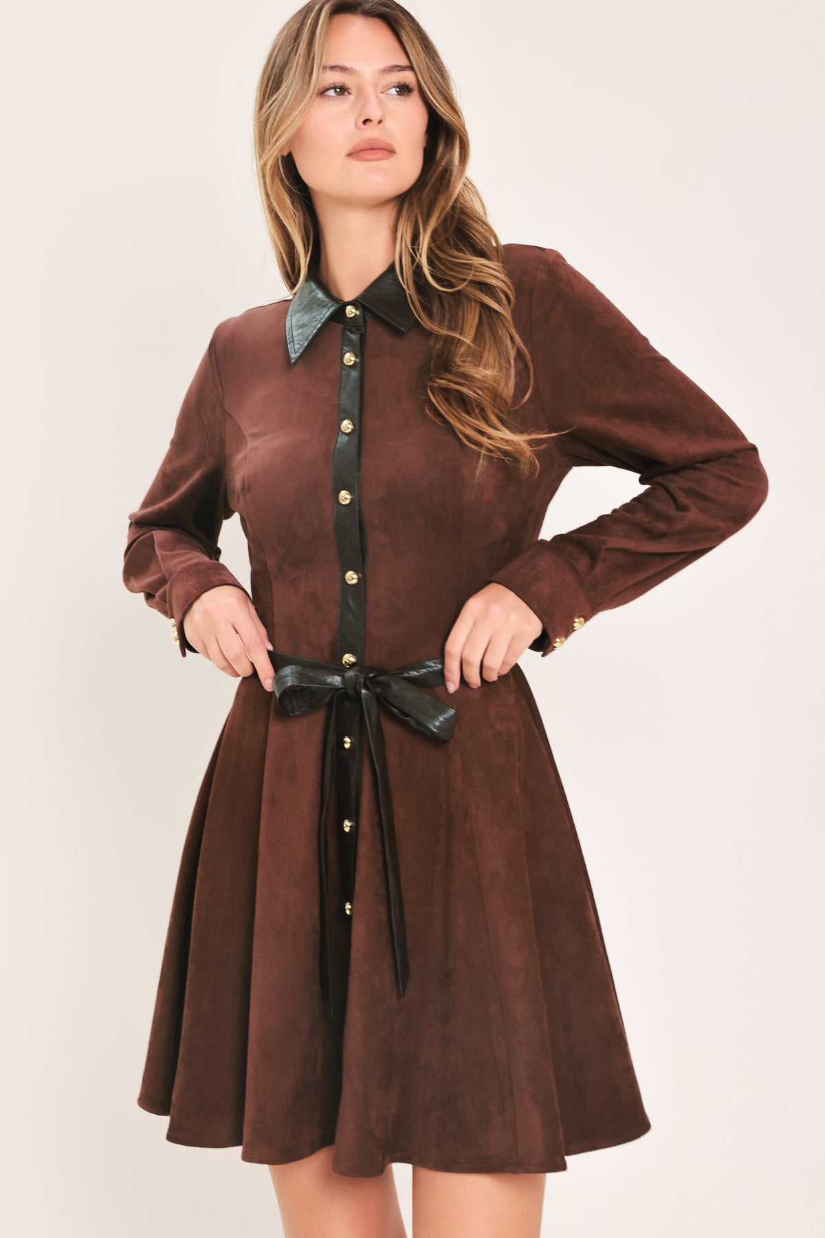 A woman modeling a burgundy suede long-sleeve shirt dress with a black faux-leather collar, button placket, and matching black tie belt | Flying Tomato