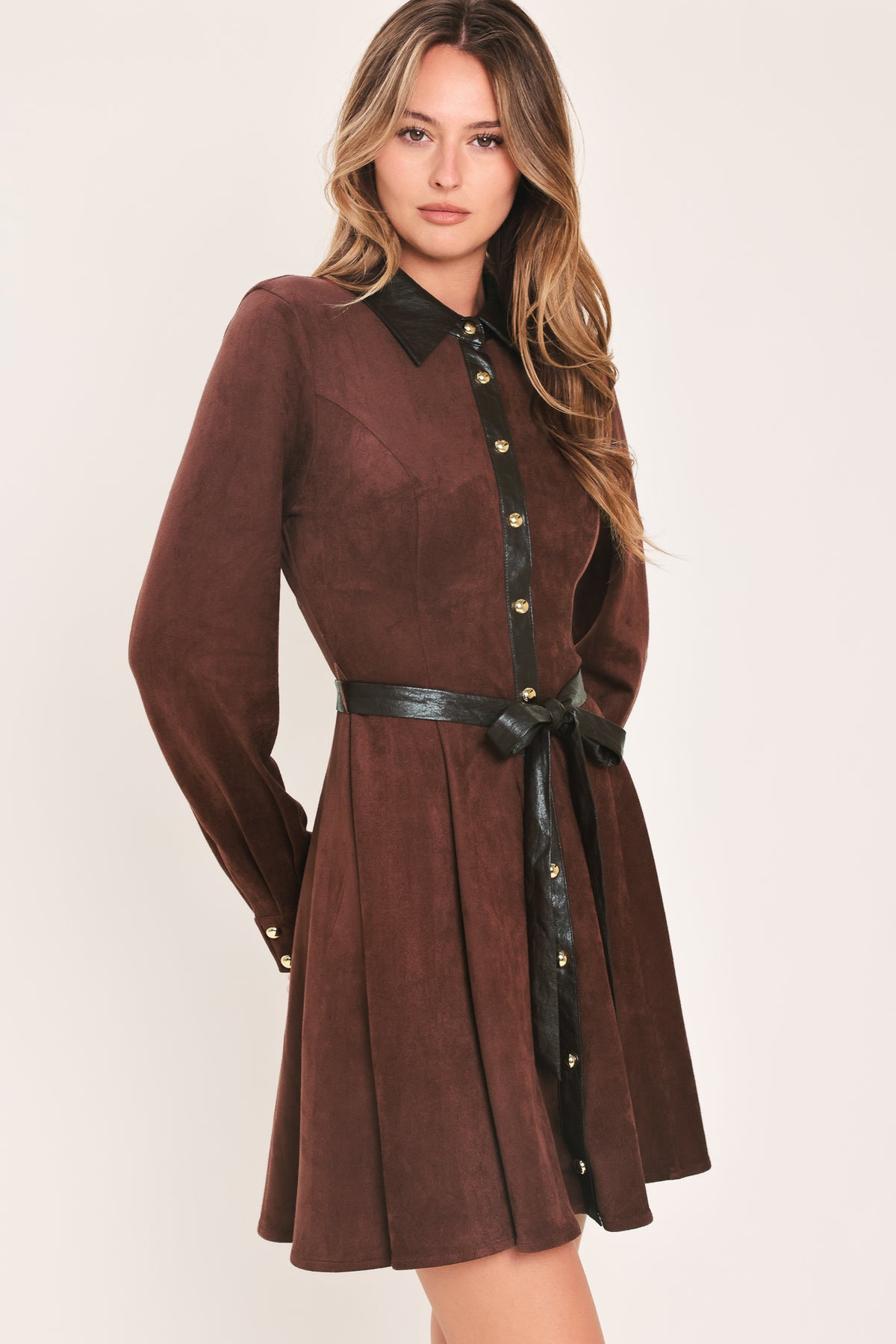 A woman modeling a burgundy suede long-sleeve shirt dress with a black faux-leather collar, button placket, and matching black tie belt | Flying Tomato