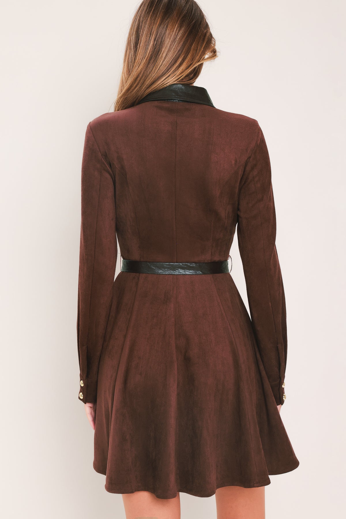 A woman modeling a burgundy suede long-sleeve shirt dress with a black faux-leather collar, button placket, and matching black tie belt | Flying Tomato