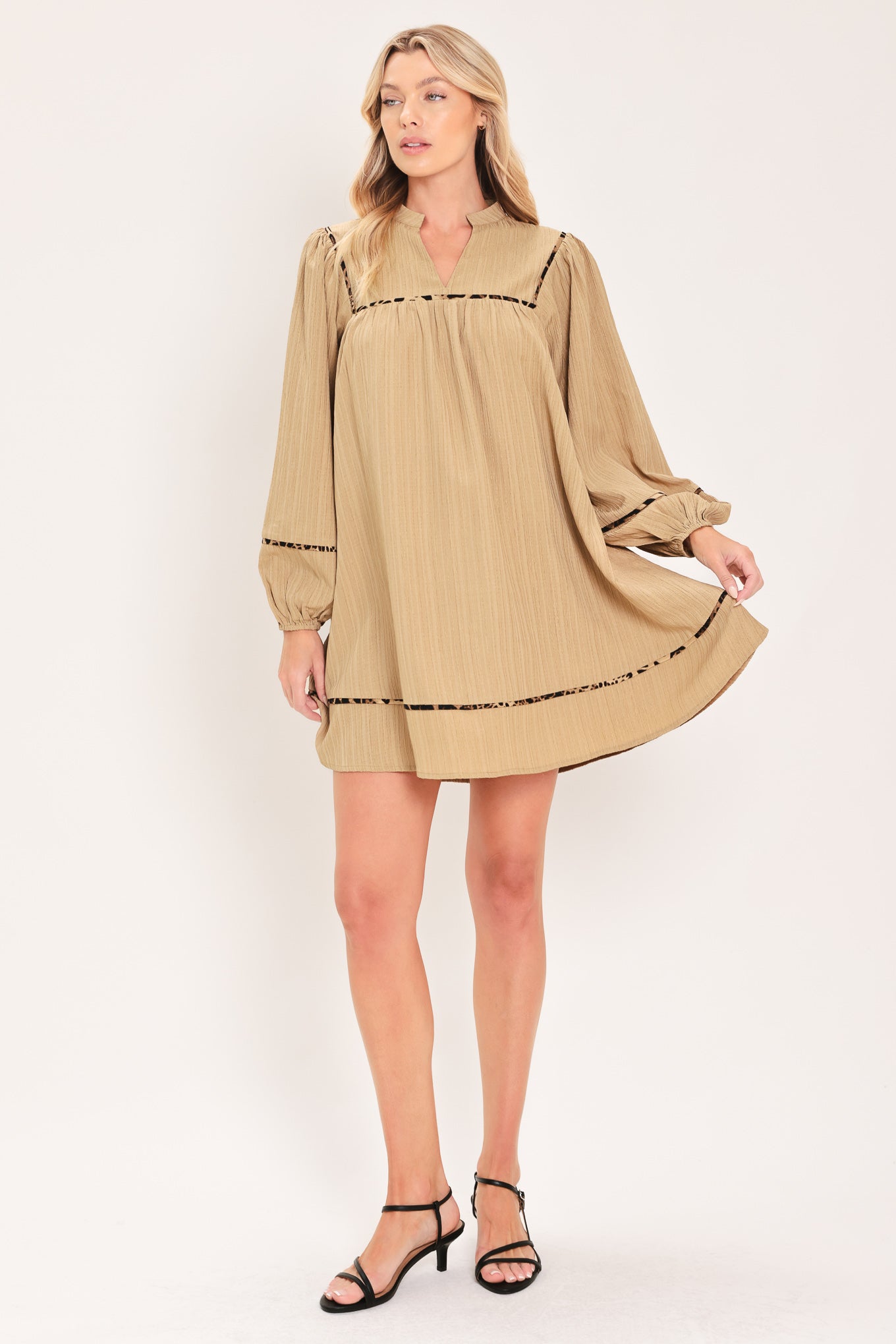 A woman wearing a beige long-sleeve mini dress with black leopard print patterned trim details | Flying Tomato