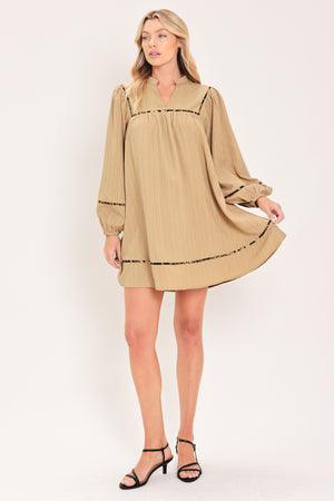A woman wearing a beige long-sleeve mini dress with black leopard print patterned trim details | Flying Tomato