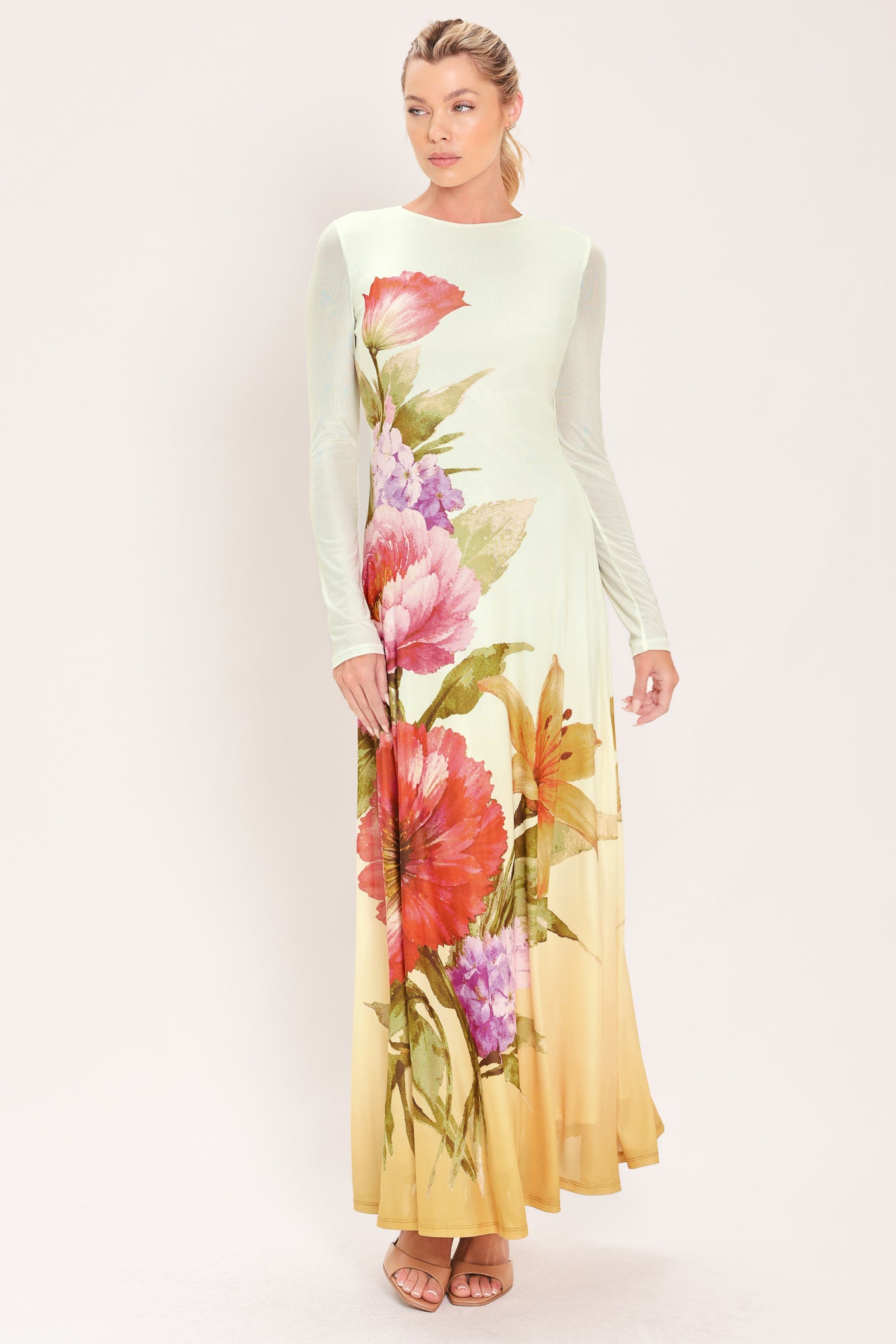 A woman modeling a long-sleeve maxi dress with a large floral print in pink, red, purple, and green | Flying Tomato