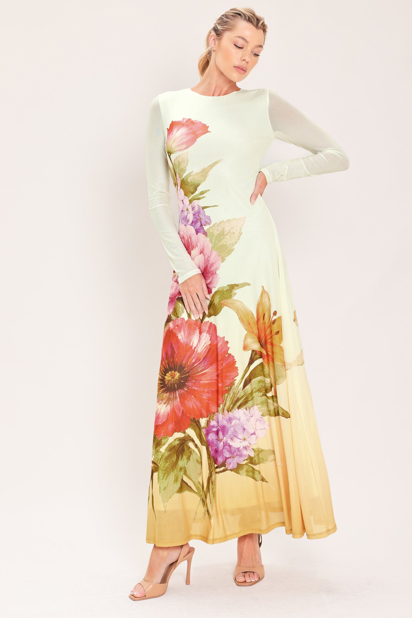 A woman modeling a long-sleeve maxi dress with a large floral print in pink, red, purple, and green | Flying Tomato