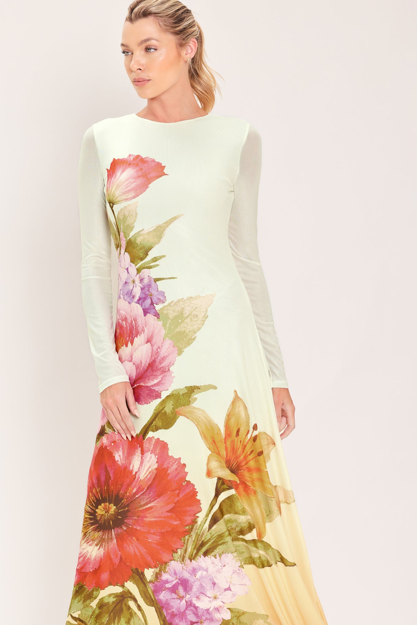 A woman modeling a long-sleeve maxi dress with a large floral print in pink, red, purple, and green | Flying Tomato