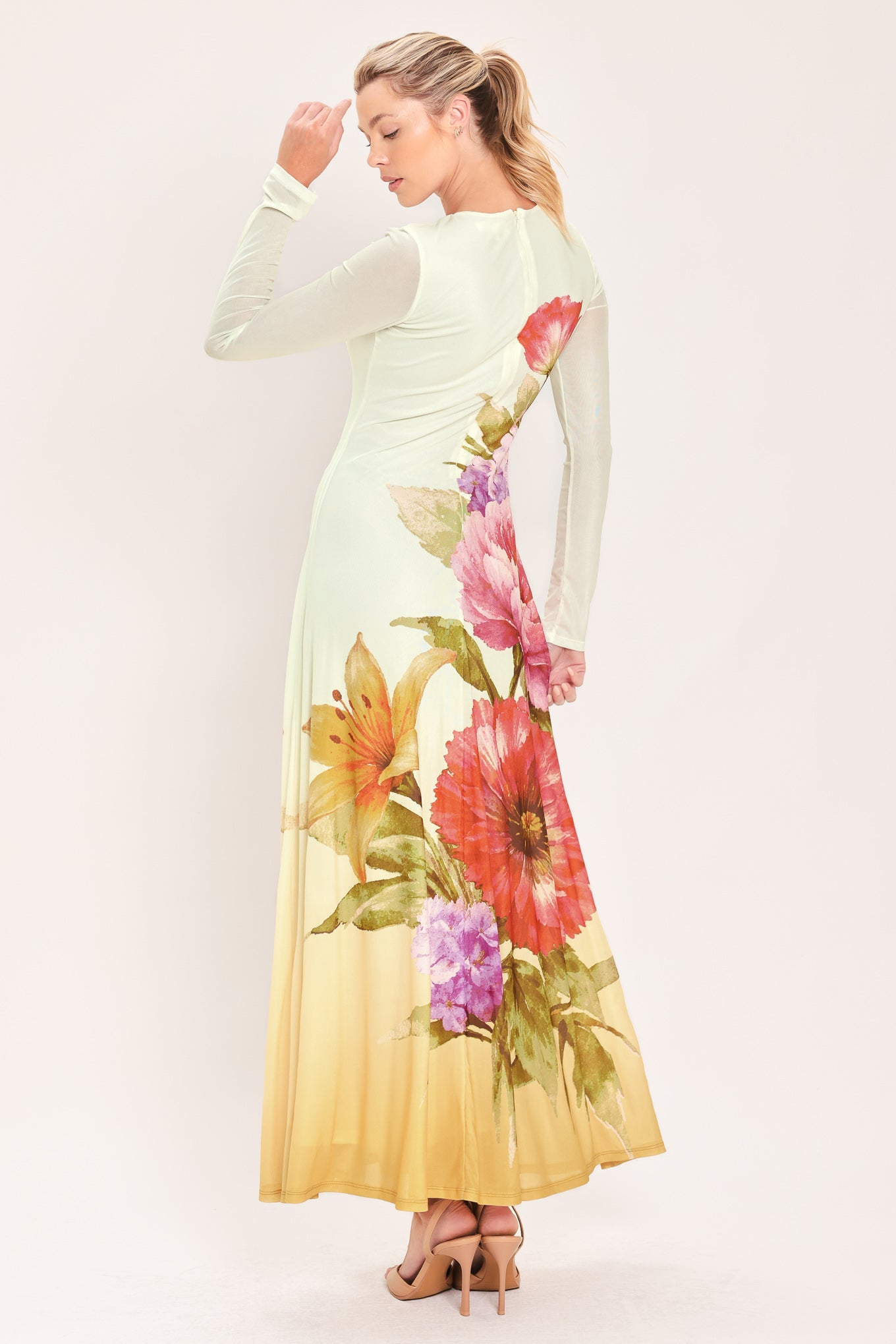 A woman modeling a long-sleeve maxi dress with a large floral print in pink, red, purple, and green | Flying Tomato