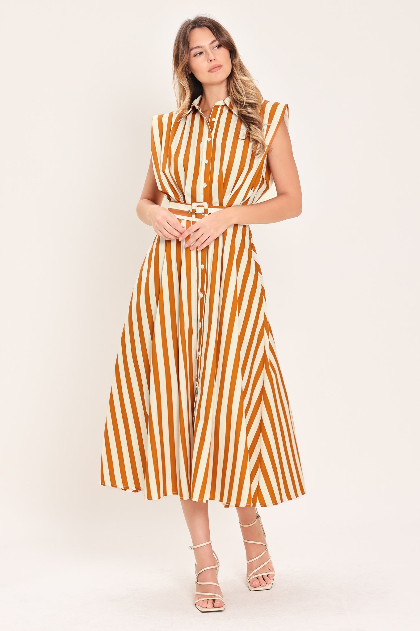 Woman wearing a sleeveless caramel and white striped dress with a belt | Flying Tomato