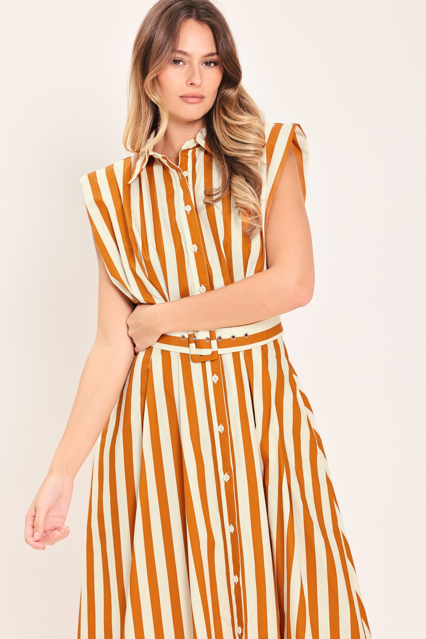 Woman wearing a sleeveless caramel and white striped dress with a belt | Flying Tomato