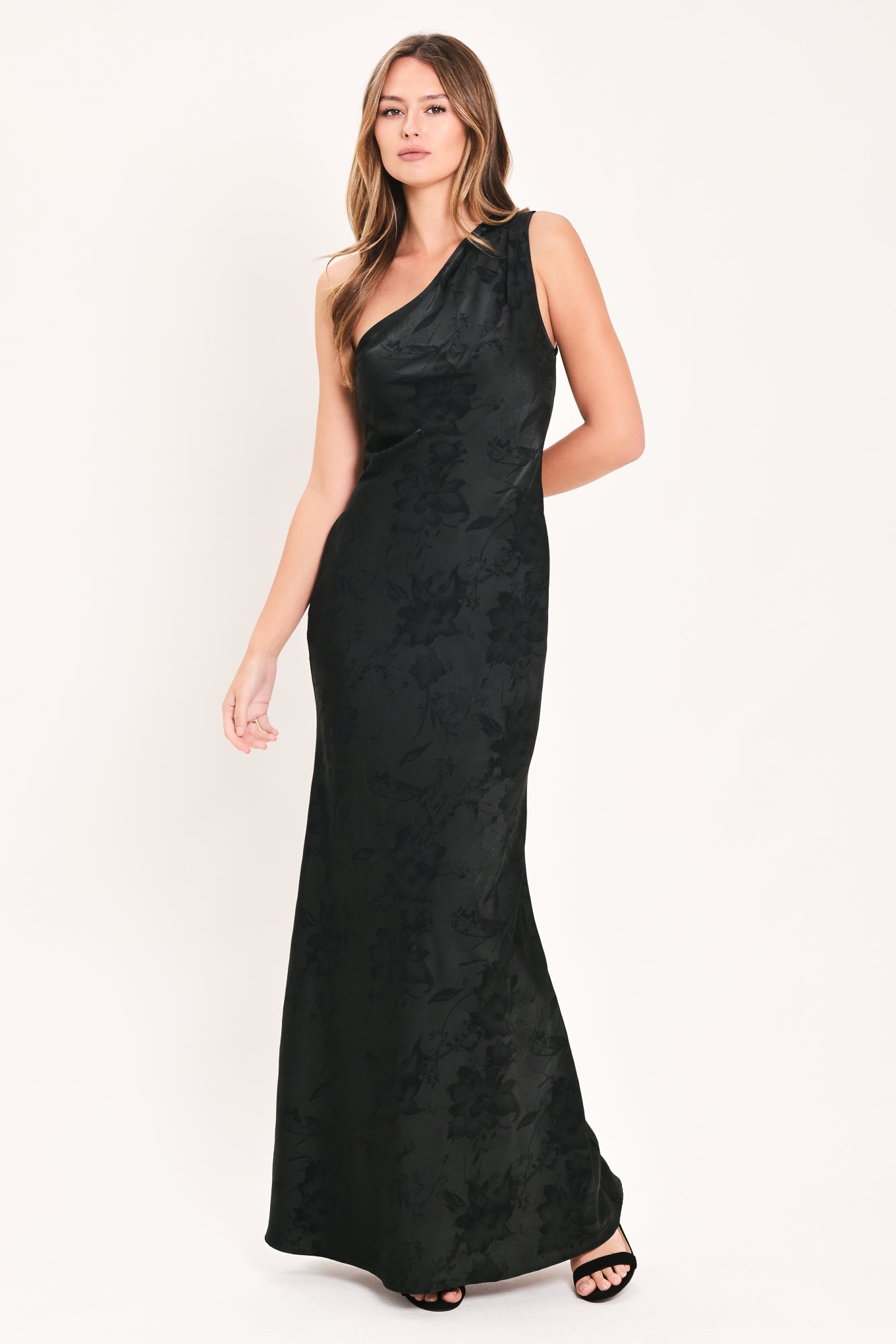 A woman modeling a sleeveless, one-shoulder black maxi dress with a textured jacquard pattern | Flying Tomato