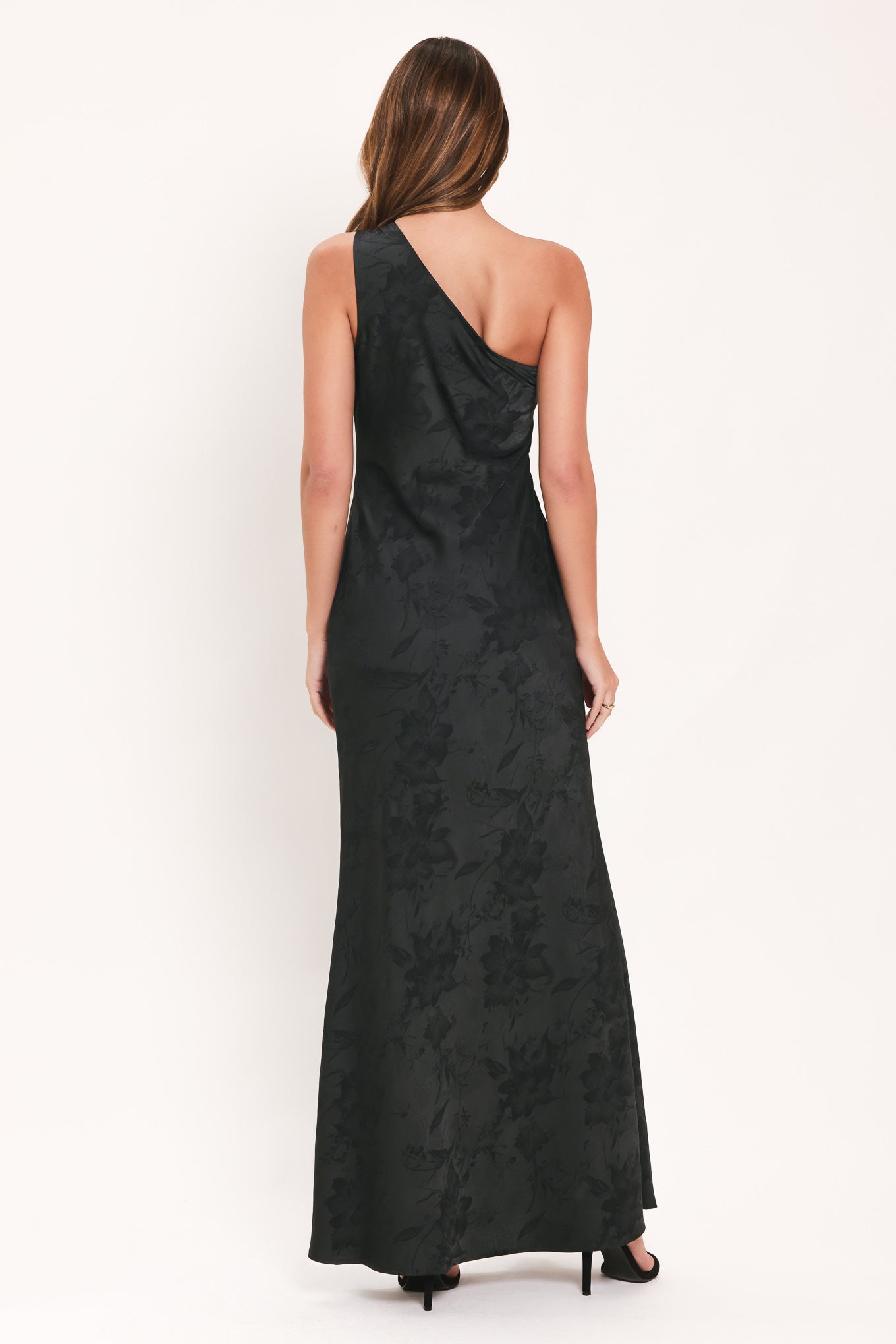 A woman modeling a sleeveless, one-shoulder black maxi dress with a textured jacquard pattern | Flying Tomato