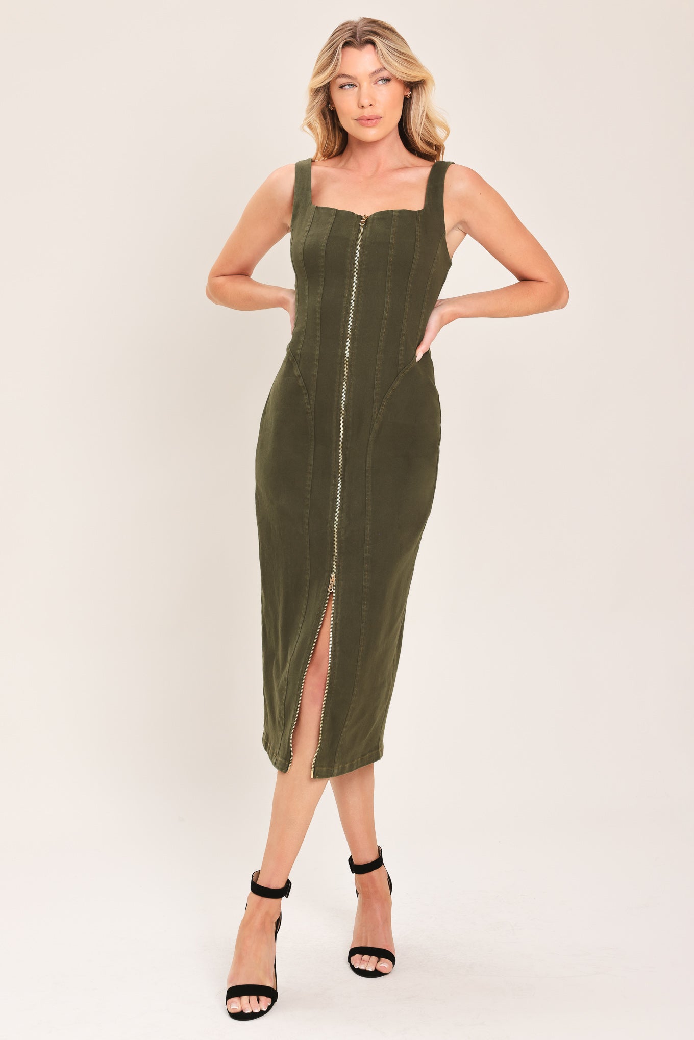 A woman wearing an olive green sleeveless midi dress with a square neckline and front zipper | Flying Tomato