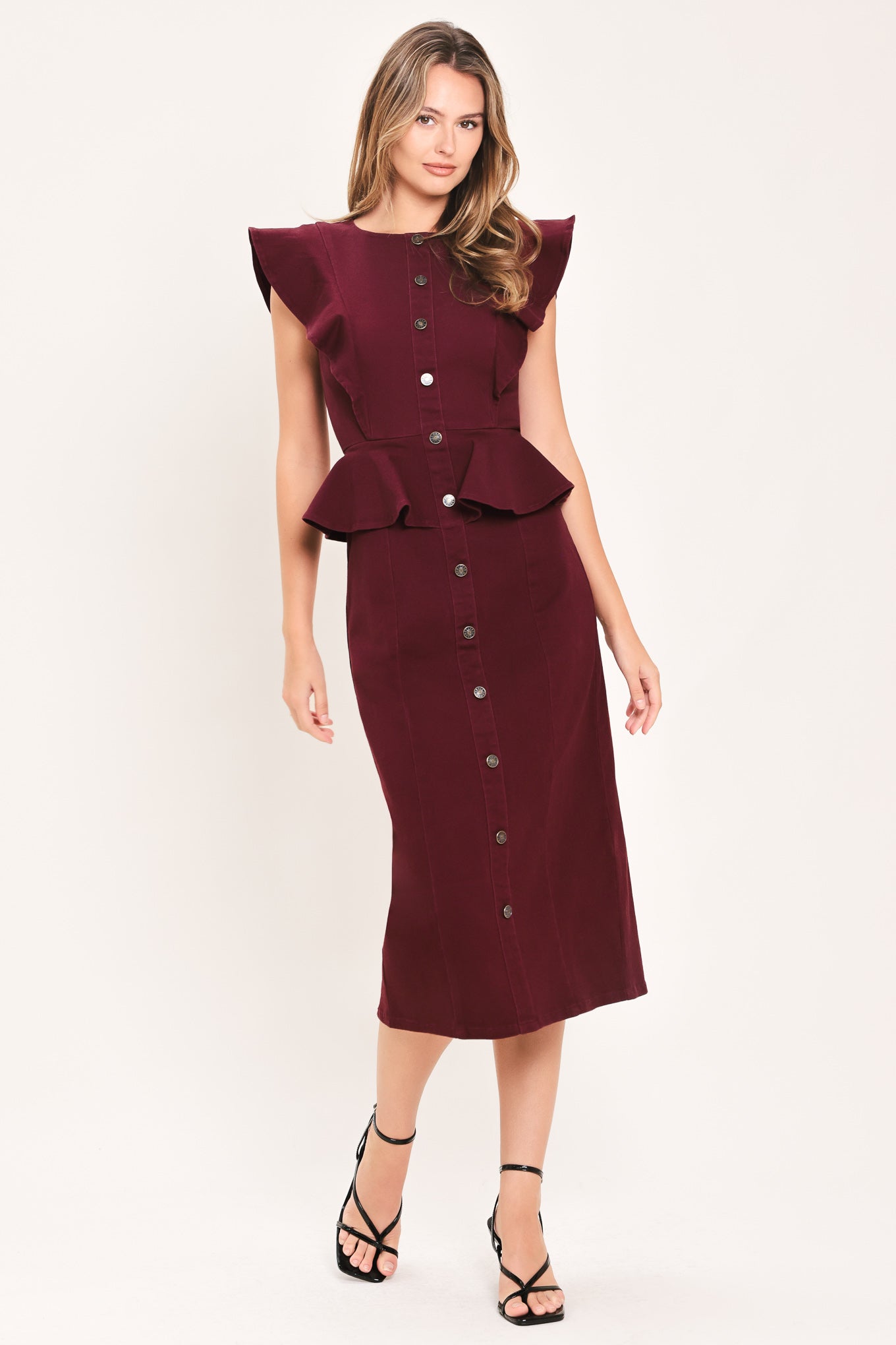 A woman modeling a sleeveless burgundy midi dress with ruffled cap sleeves, a peplum waist, and a front button placket | Flying Tomato