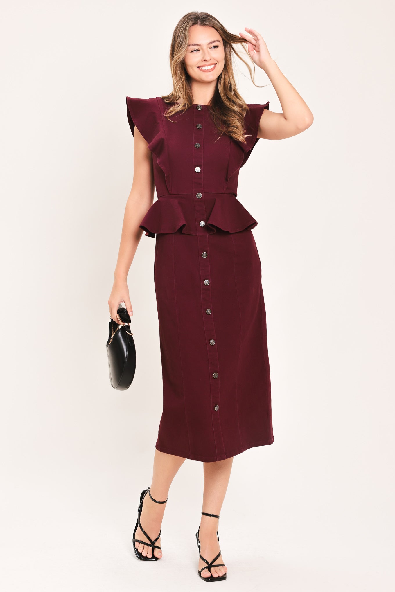 A woman modeling a sleeveless burgundy midi dress with ruffled cap sleeves, a peplum waist, and a front button placket | Flying Tomato