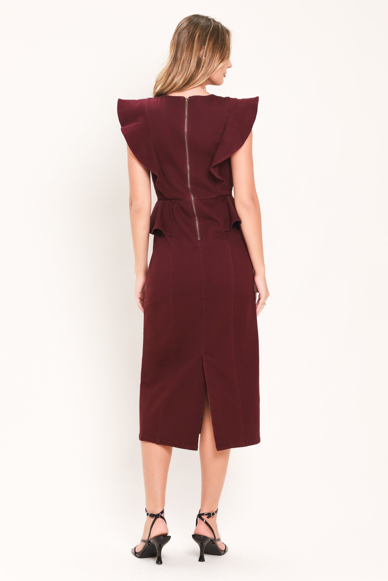 A woman modeling a sleeveless burgundy midi dress with ruffled cap sleeves, a peplum waist, and a front button placket | Flying Tomato
