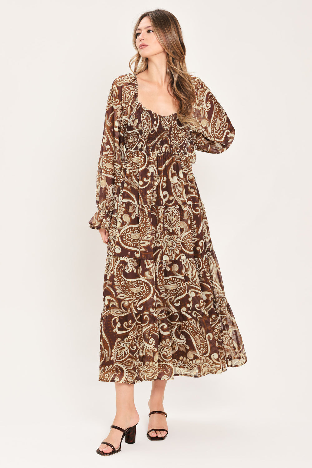 A woman wearing a long-sleeved midi dress with a brown and beige paisley pattern | Flying Tomato