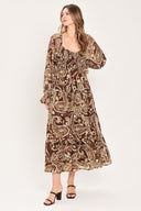 A woman wearing a long-sleeved midi dress with a brown and beige paisley pattern | Flying Tomato