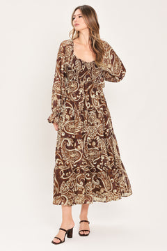 A woman wearing a long-sleeved midi dress with a brown and beige paisley pattern | Flying Tomato