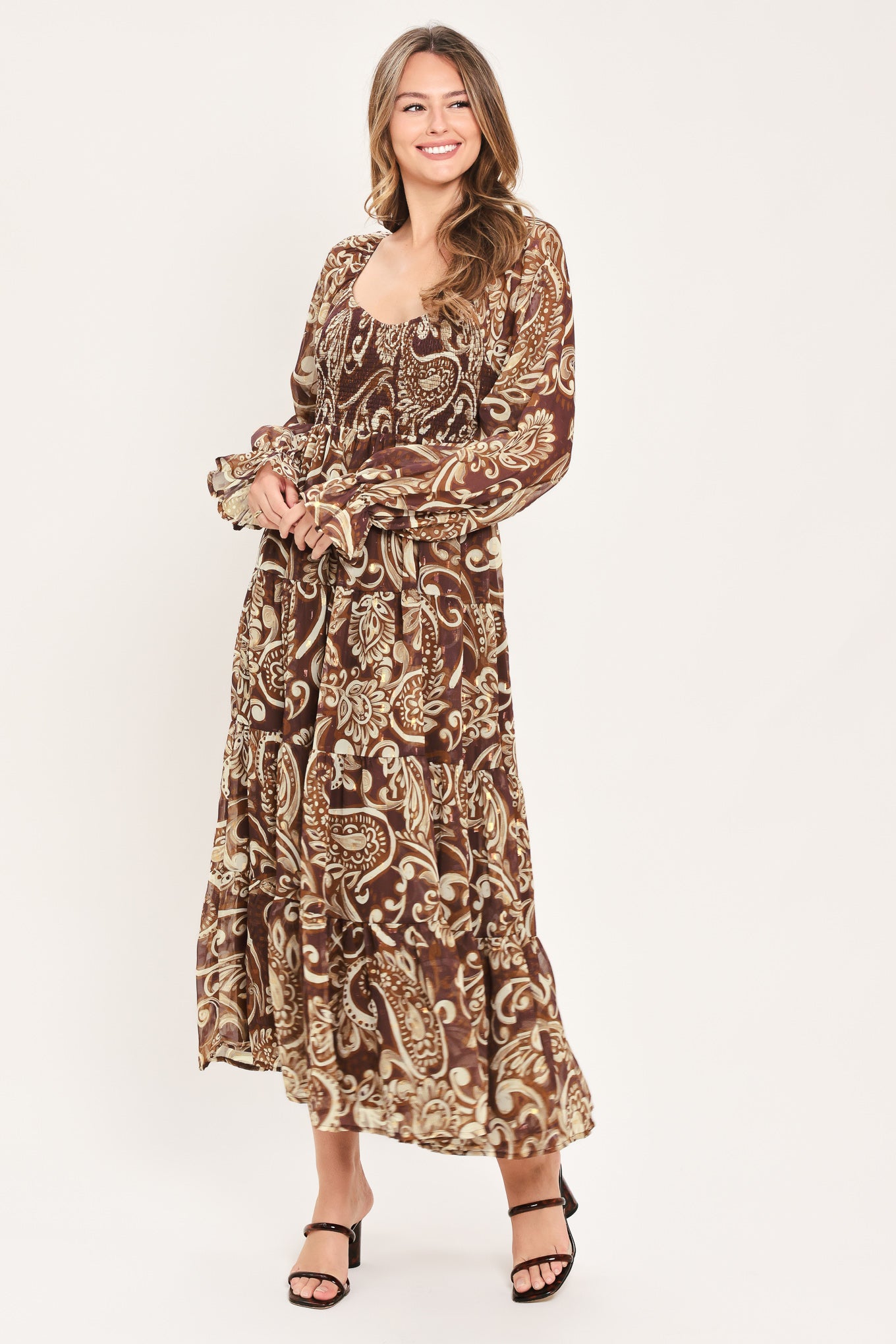 A woman wearing a long-sleeved midi dress with a brown and beige paisley pattern | Flying Tomato